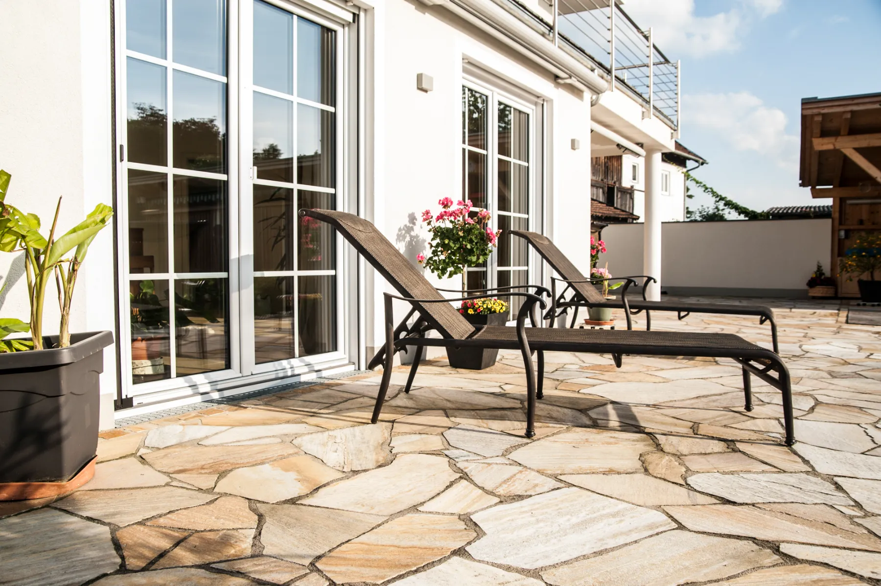 Natural stone terrace with sun loungers in front of a modern house — landscape architecture photographed by Janina Laszlo for Ammerseer Landschaftsbau in the Ammersee region, Bavaria