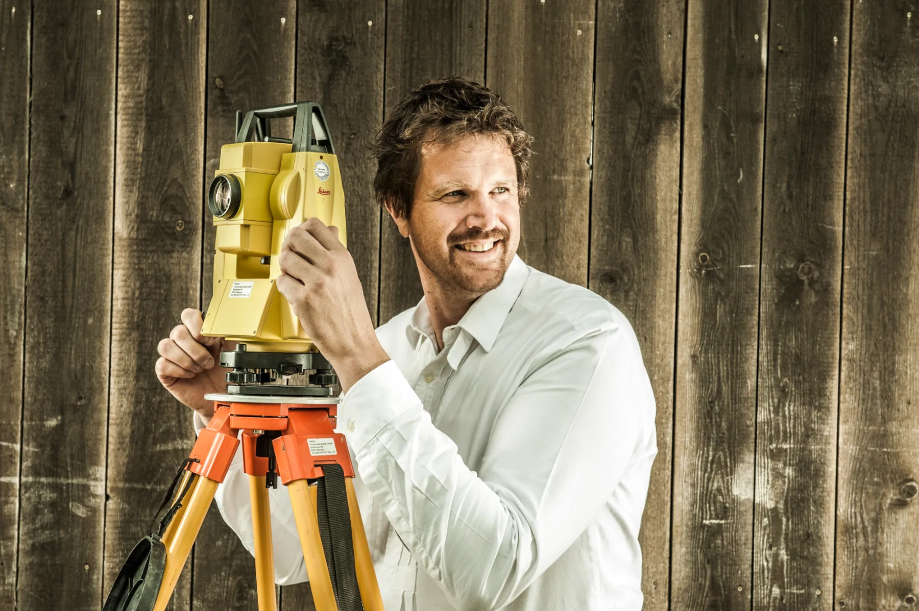 Team member in a white shirt at a surveying instrument on a tripod — brand portrait by Janina Laszlo for Ammerseer Landschaftsbau, professional landscaping company in Bavaria