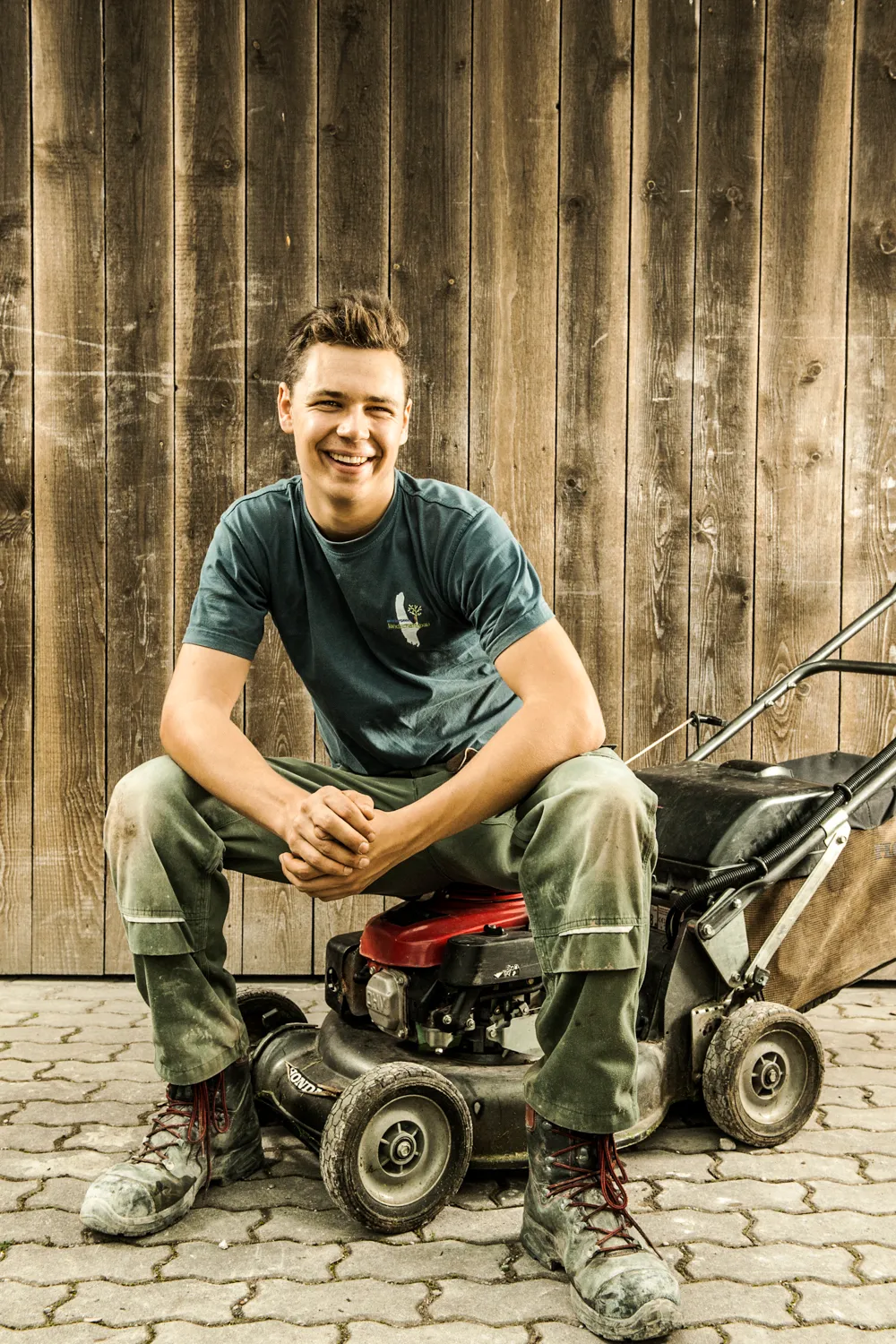 Smiling team member sitting on a mini dumper — commercial and brand photography by Janina Laszlo for Ammerseer Landschaftsbau, professional landscaping company in Bavaria