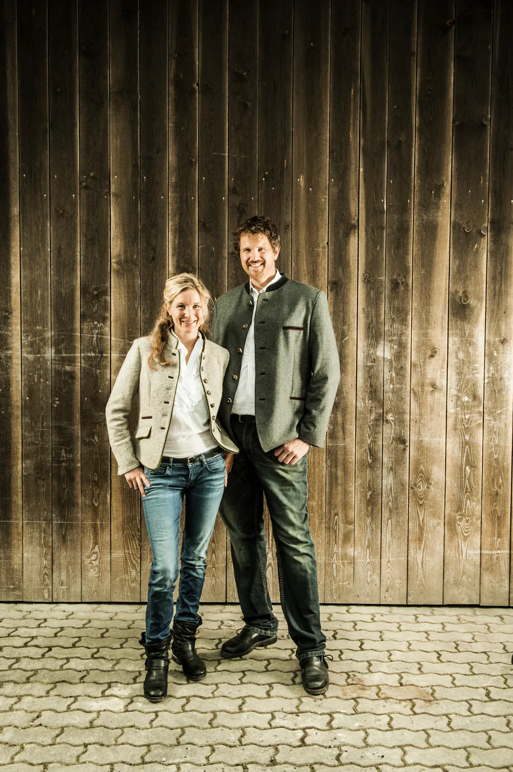 Two people standing together in front of a wooden wall on a cobblestone floor — brand portrait by Janina Laszlo for Ammerseer Landschaftsbau, Ammersee region, Bavaria