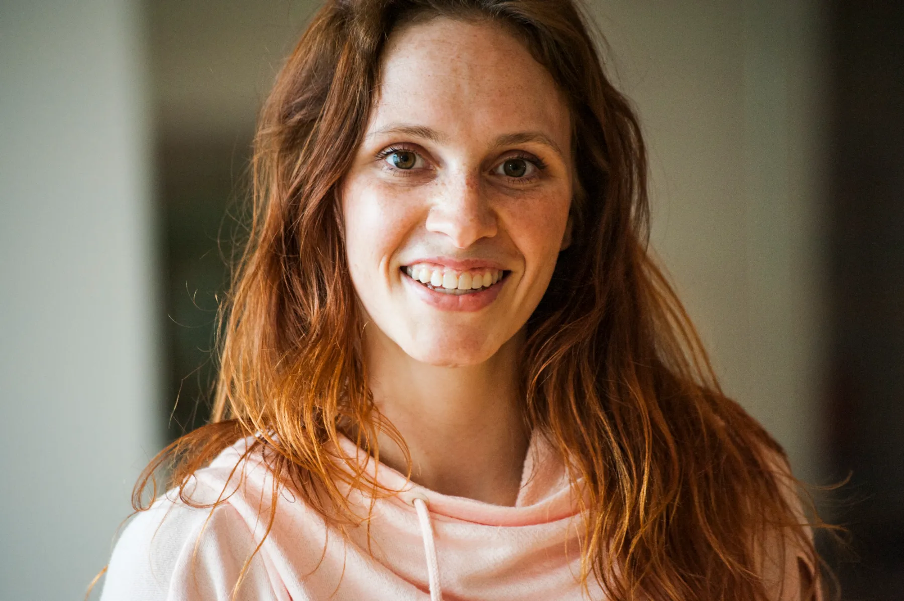 Smiling close-up portrait of dancer and actress Kassandra Wedel in a pink hoodie — authentic portraiture for the AOK healthcare campaign by Janina Laszlo, Munich