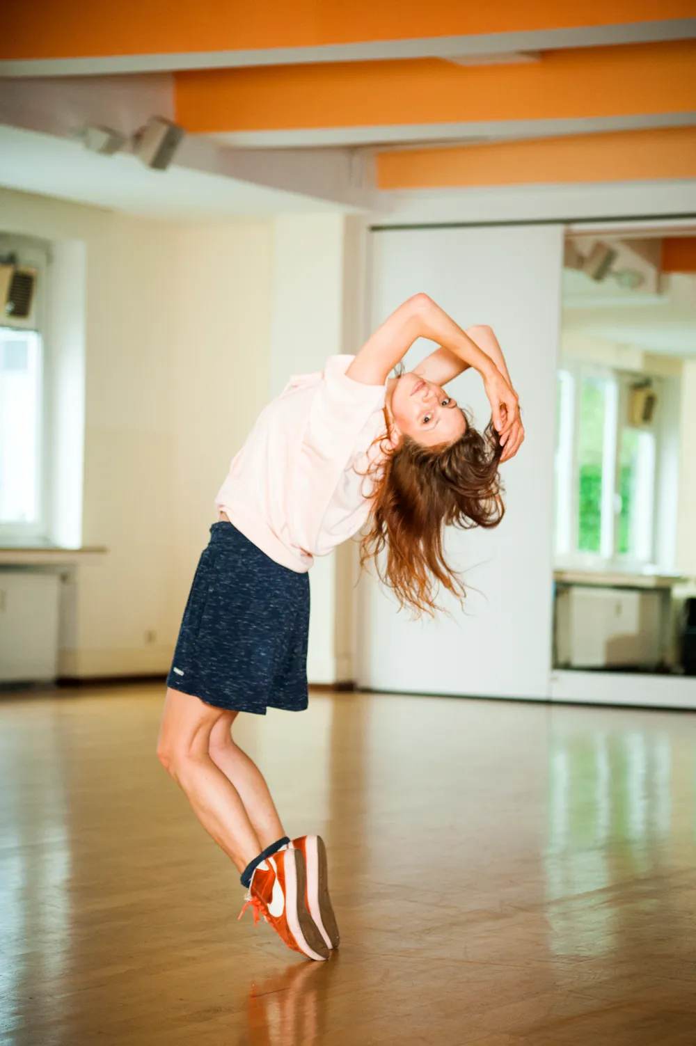 Kassandra Wedel dancing on tiptoe in red sneakers in a bright dance studio — movement and visual storytelling in the AOK campaign by photographer Janina Laszlo