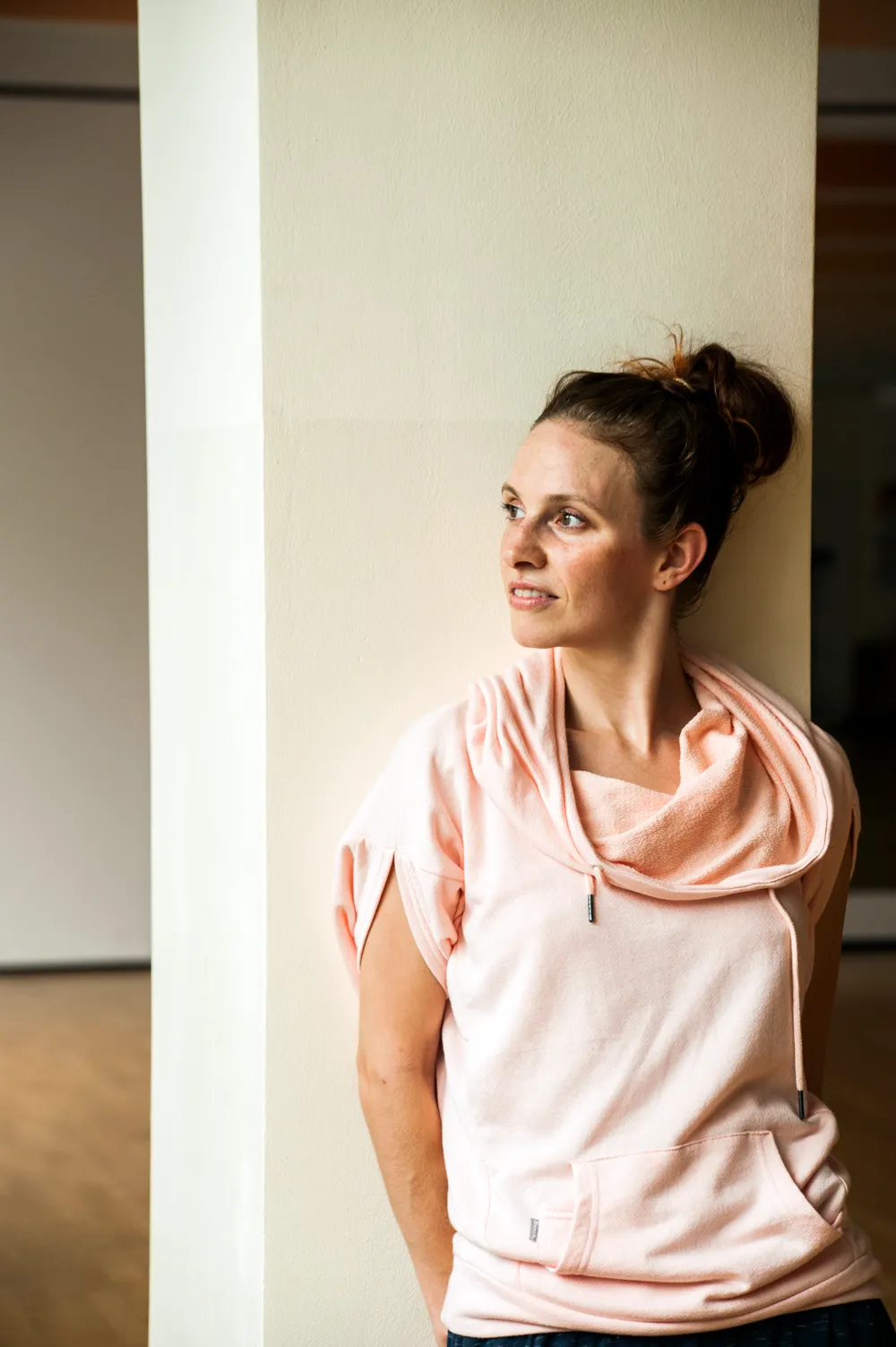 Kassandra Wedel leaning against a white pillar, looking out of the frame — editorial portrait for the AOK healthcare brand campaign by German photographer Janina Laszlo