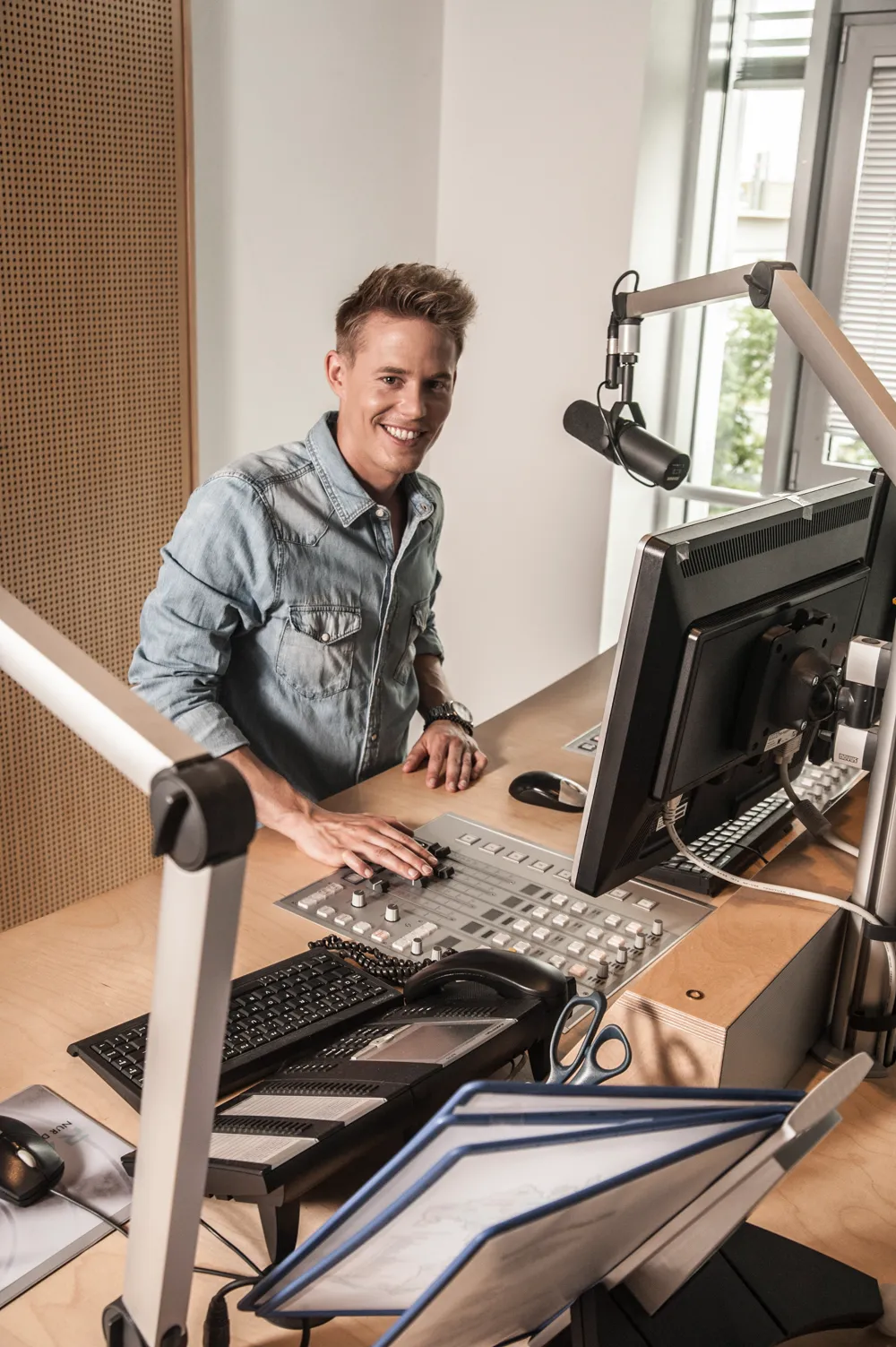 Timo Killer standing at a studio console with a microphone arm in the foreground — commercial and editorial photography by Janina Laszlo for AOK