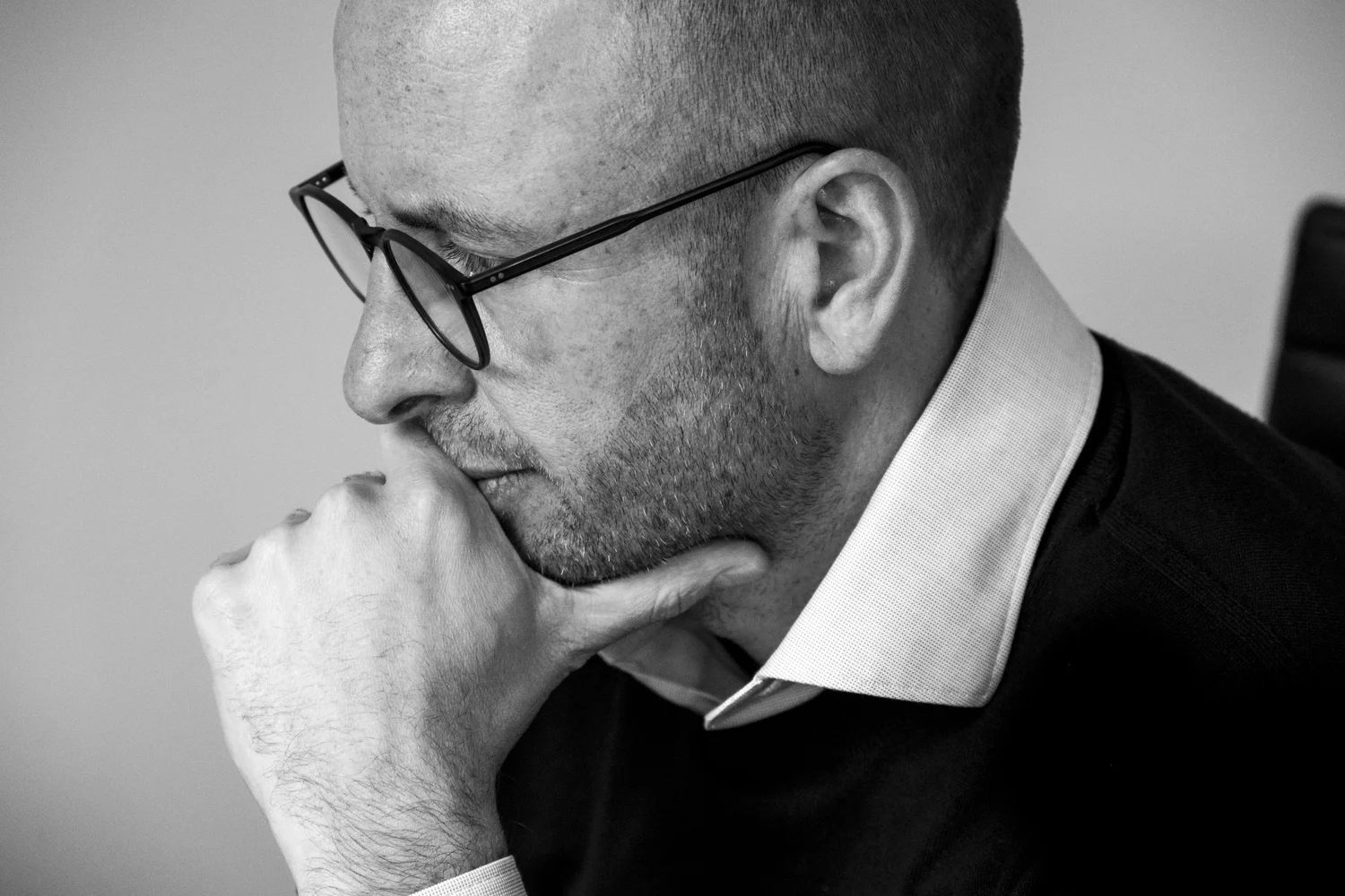 Black-and-white close-up of an architect with glasses resting his chin on his hand, Helmling — portrait by Janina Laszlo, portrait photographer in Munich