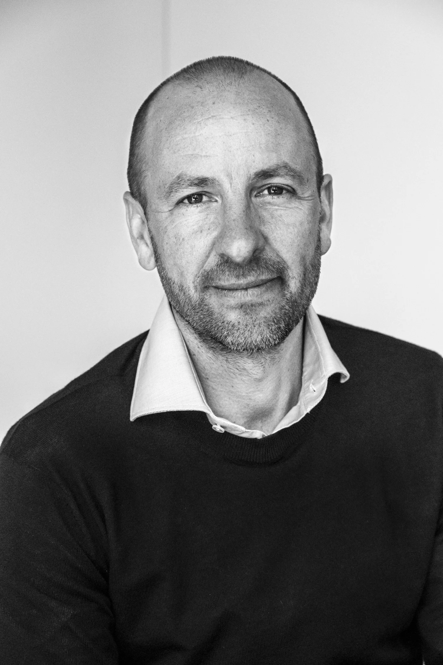 Black-and-white headshot of a smiling architect in a dark sweater, architectural office Helmling — portrait by Janina Laszlo, portrait photographer in Munich