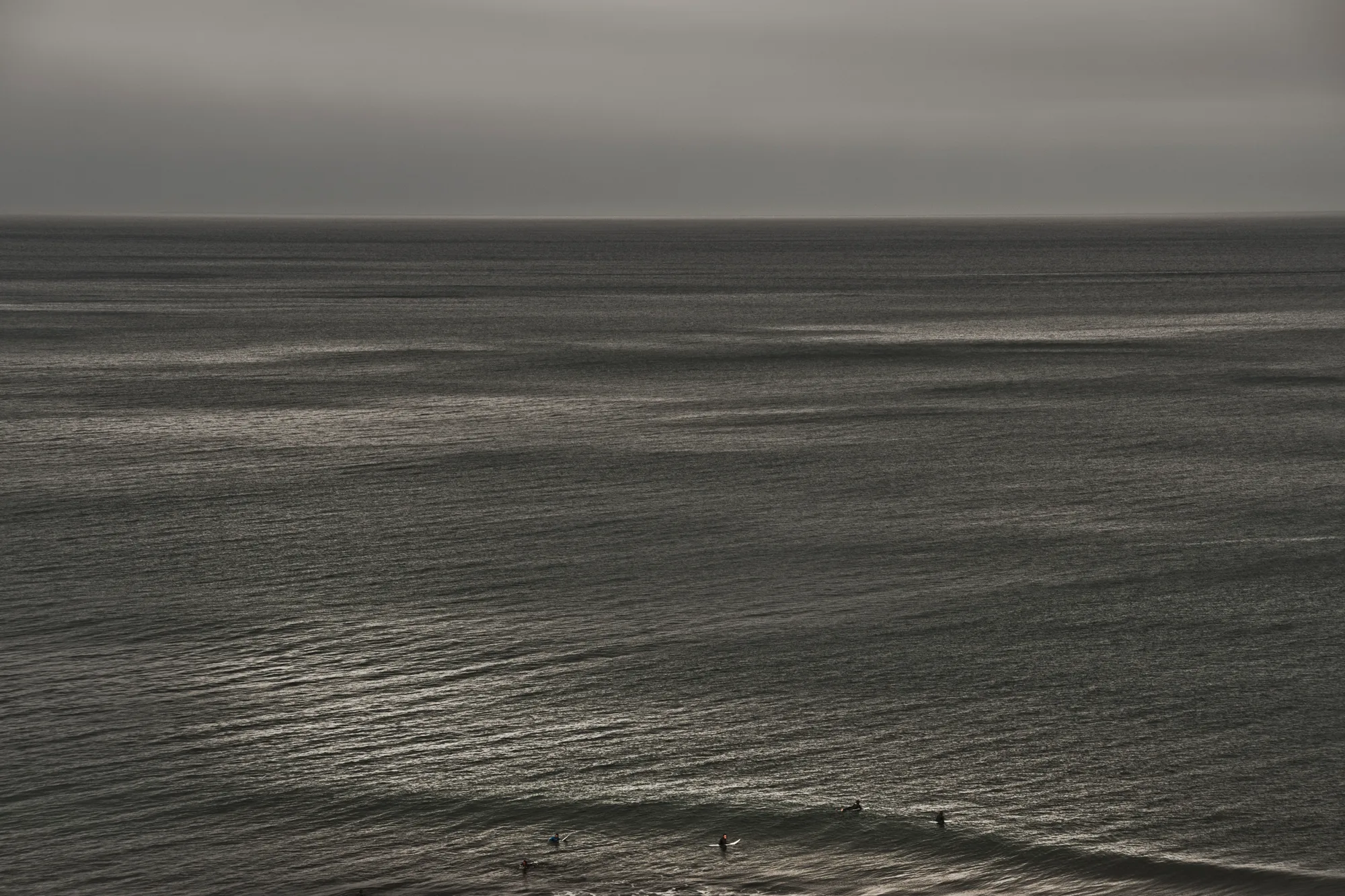 Surfers waiting in a vast, silver-grey ocean — Australia, travel and fine art photography by Janina Laszlo