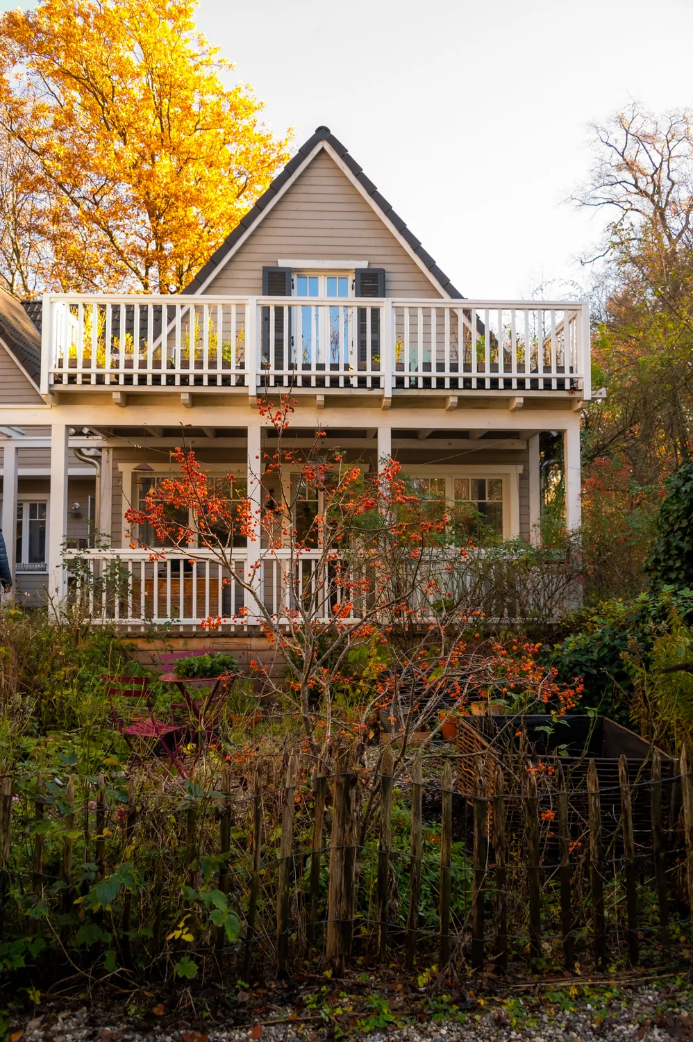 White wooden cottage with veranda among autumn trees — Autumn at My Cottage Garden, Sarah Stiller — campaign photography by Janina Laszlo, Munich