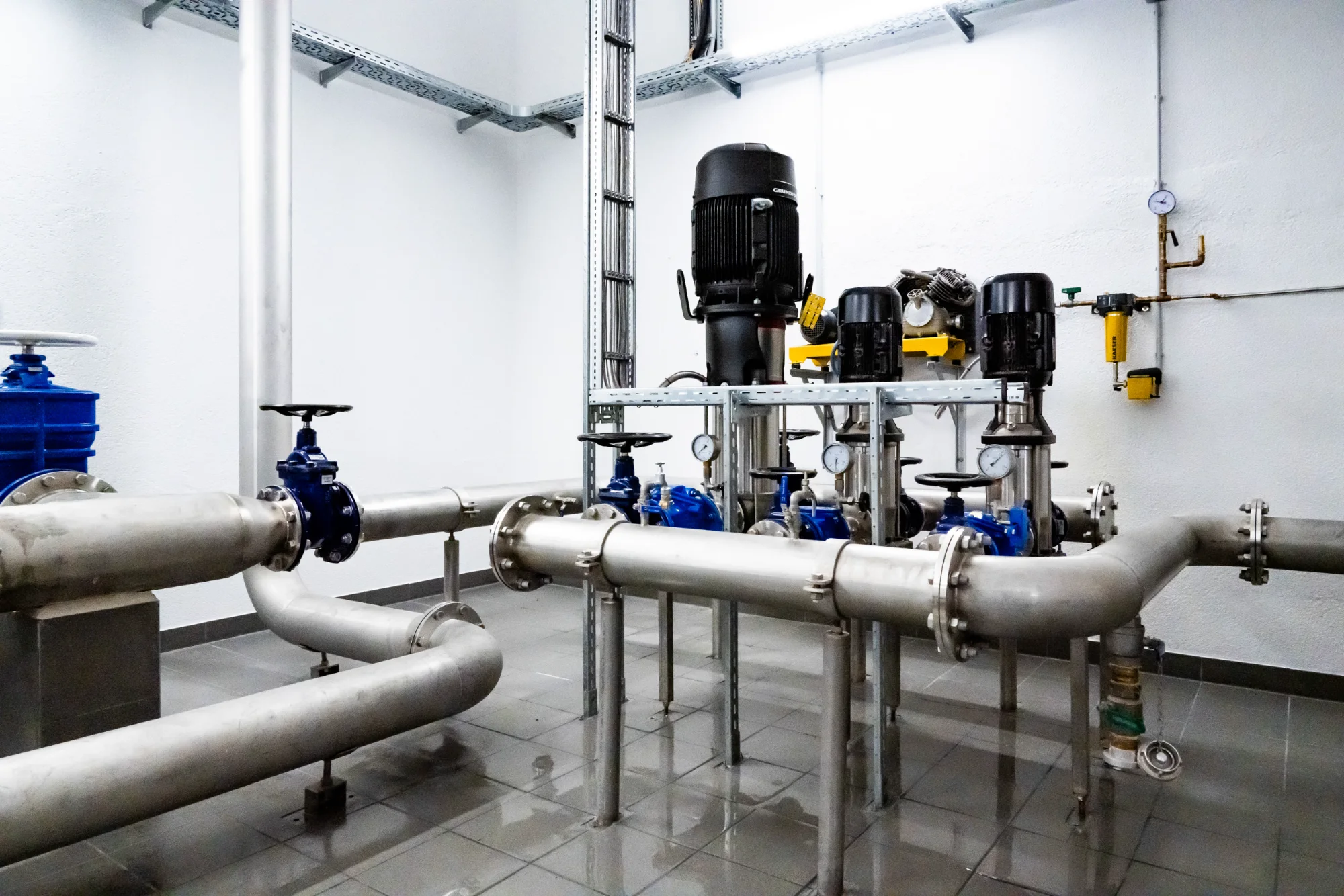 Stainless steel pipes, pumps and blue valves in a waterworks plant room — AWA Ammersee, industrial, corporate and portrait photography by Janina Laszlo