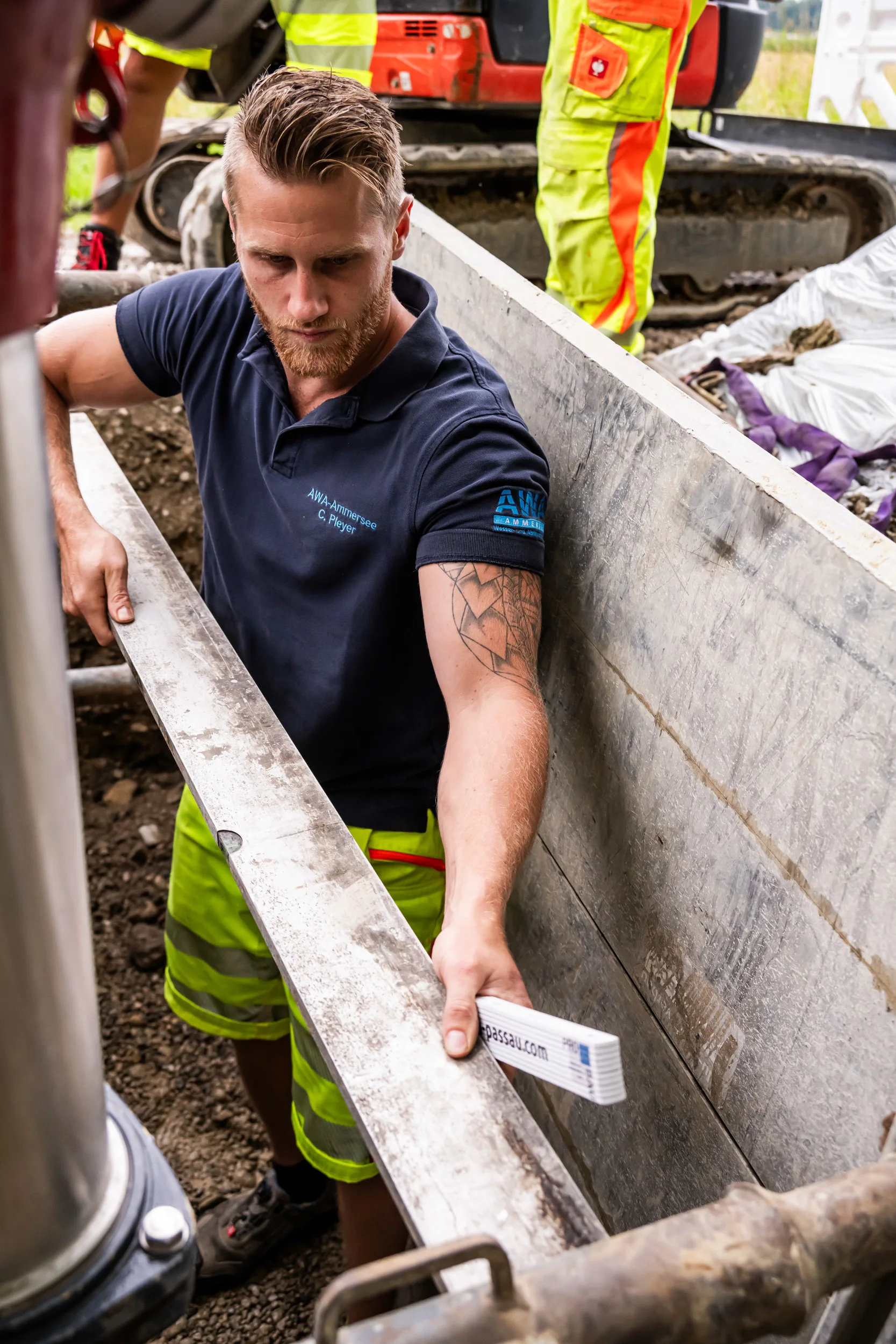 Pipe fitter climbing out of a trench with a lined pipe section — AWA Ammersee, industrial, corporate and portrait photography by Janina Laszlo