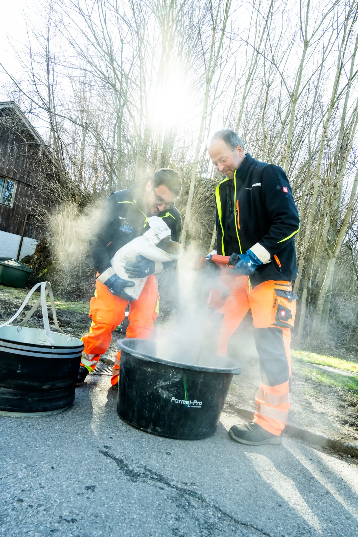 Sewer workers in rising steam at an open manhole in winter light — AWA Ammersee, industrial, corporate and portrait photography by Janina Laszlo