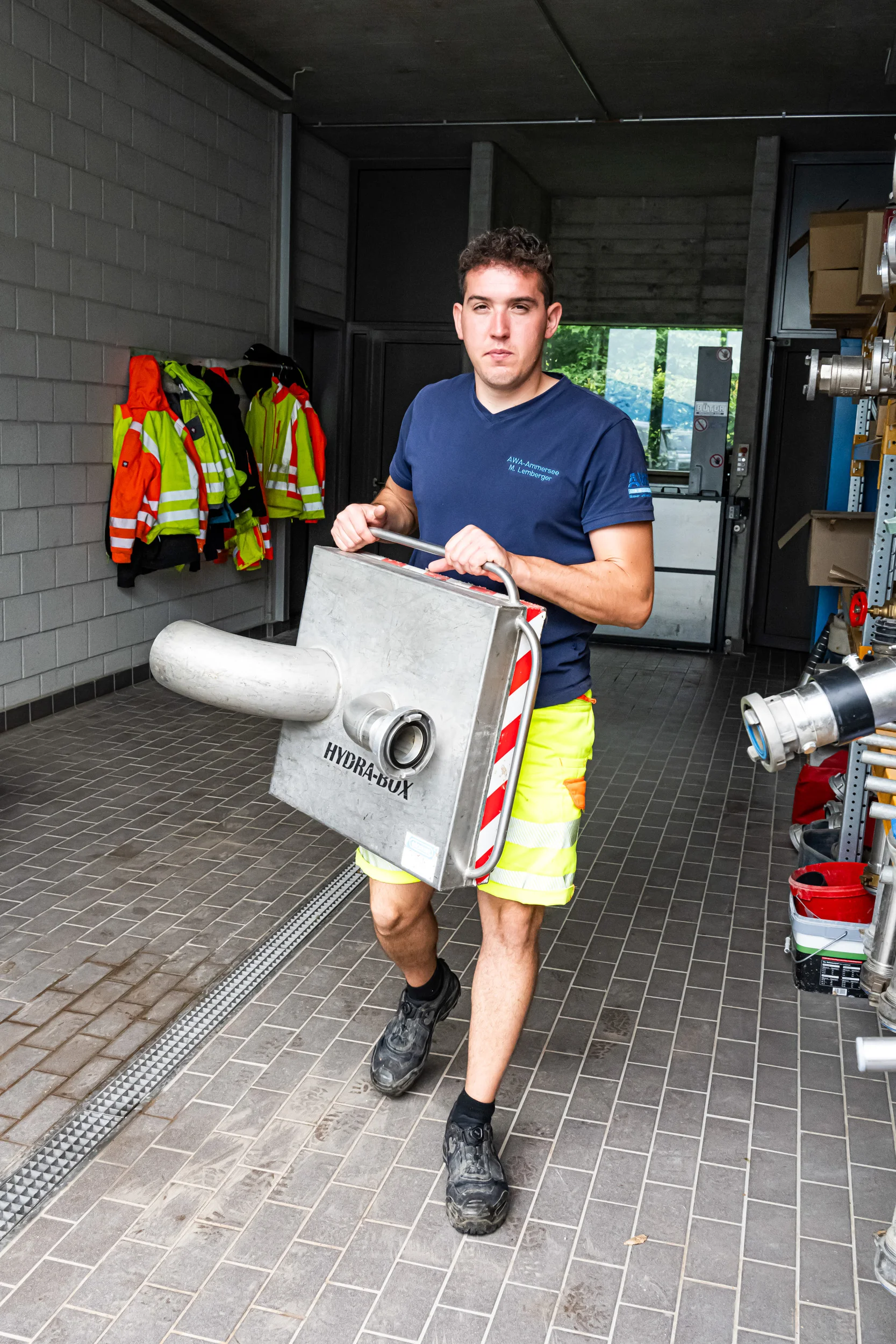 Technician carrying a valve part through the depot workshop — AWA Ammersee, industrial, corporate and portrait photography by Janina Laszlo
