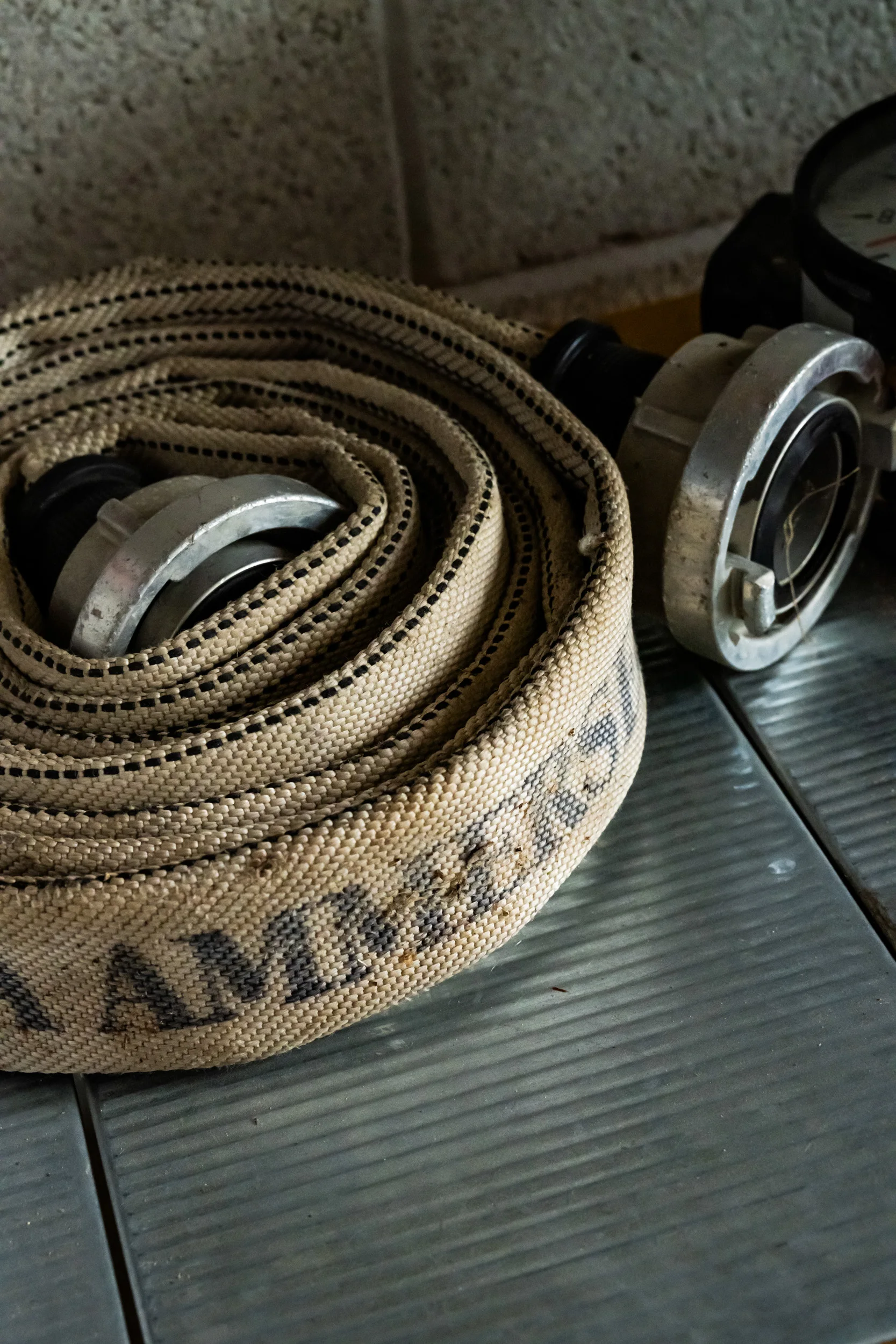 Coiled fire hose with steel couplings, close-up — AWA Ammersee, industrial, corporate and portrait photography by Janina Laszlo