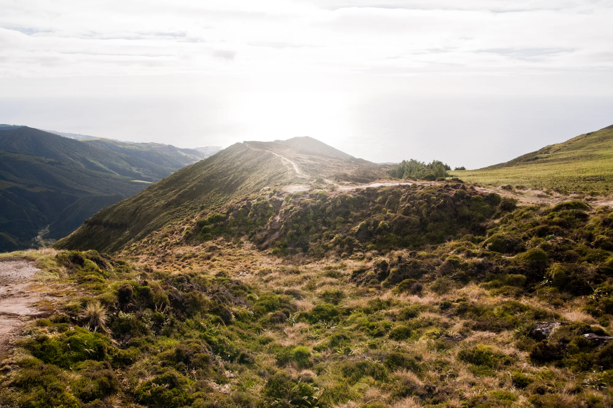 Ridge trail along a grassy crater rim with the sea shining beyond — Azores, São Miguel, travel and fine art photography by Janina Laszlo