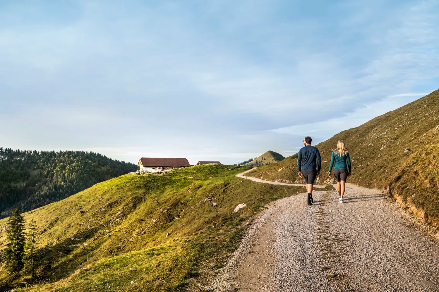 Two hikers walking up a grassy ridge trail in the Bavarian Prealps, Blaues Land, Bayerischer Tourismusverband — campaign photography by Janina Laszlo, Munich
