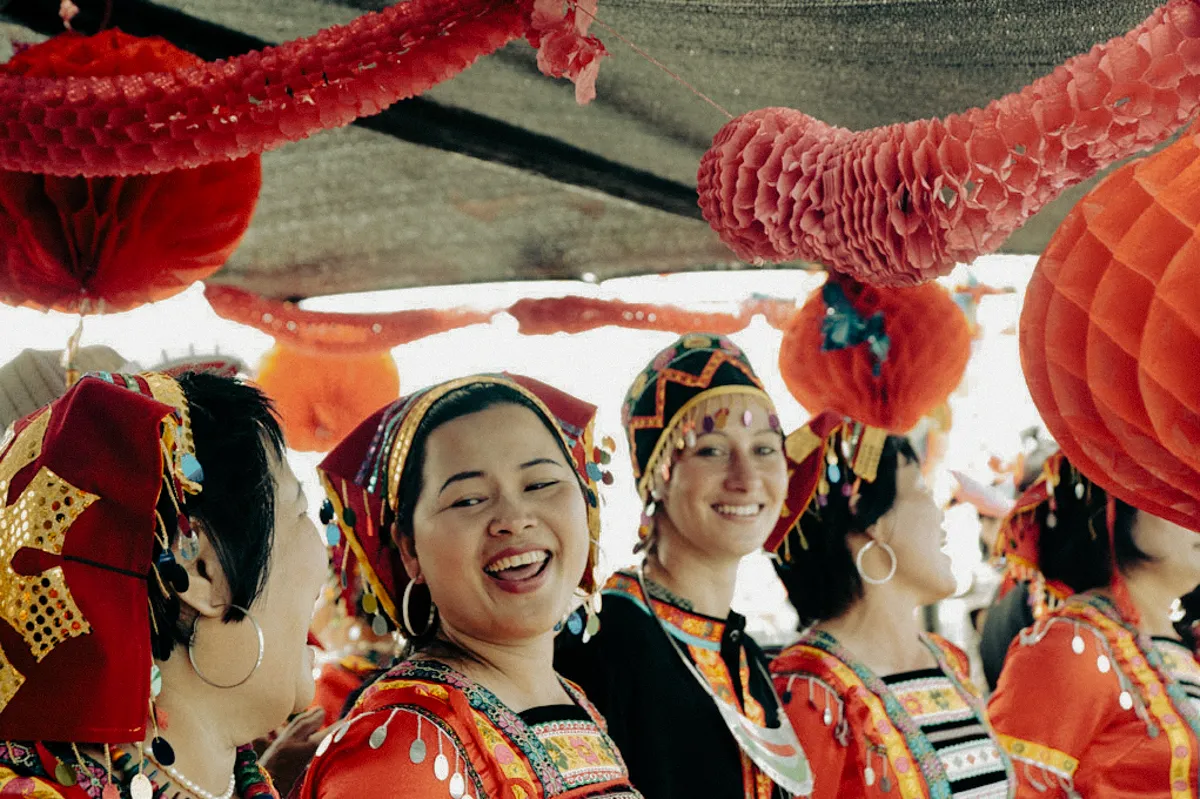 Janina Laszlo in traditional festival dress among laughing women at the Dragon Boat Festival in Hainan — behind the scenes with the German commercial and editorial photographer