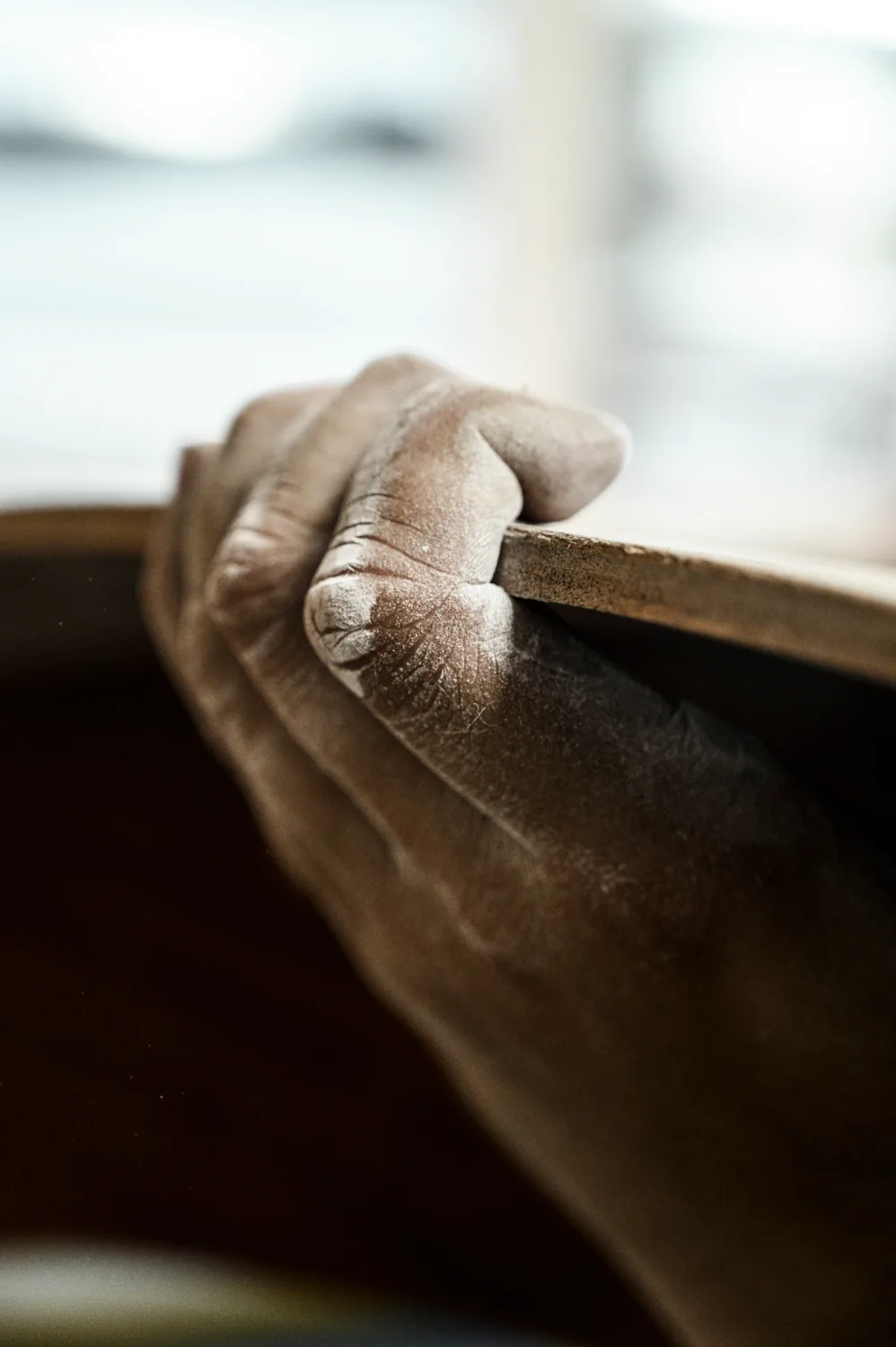 Dust-covered hand gripping the edge of a wooden hull plank, shallow depth of field — commercial and editorial photography by Janina Laszlo, photographer in Munich