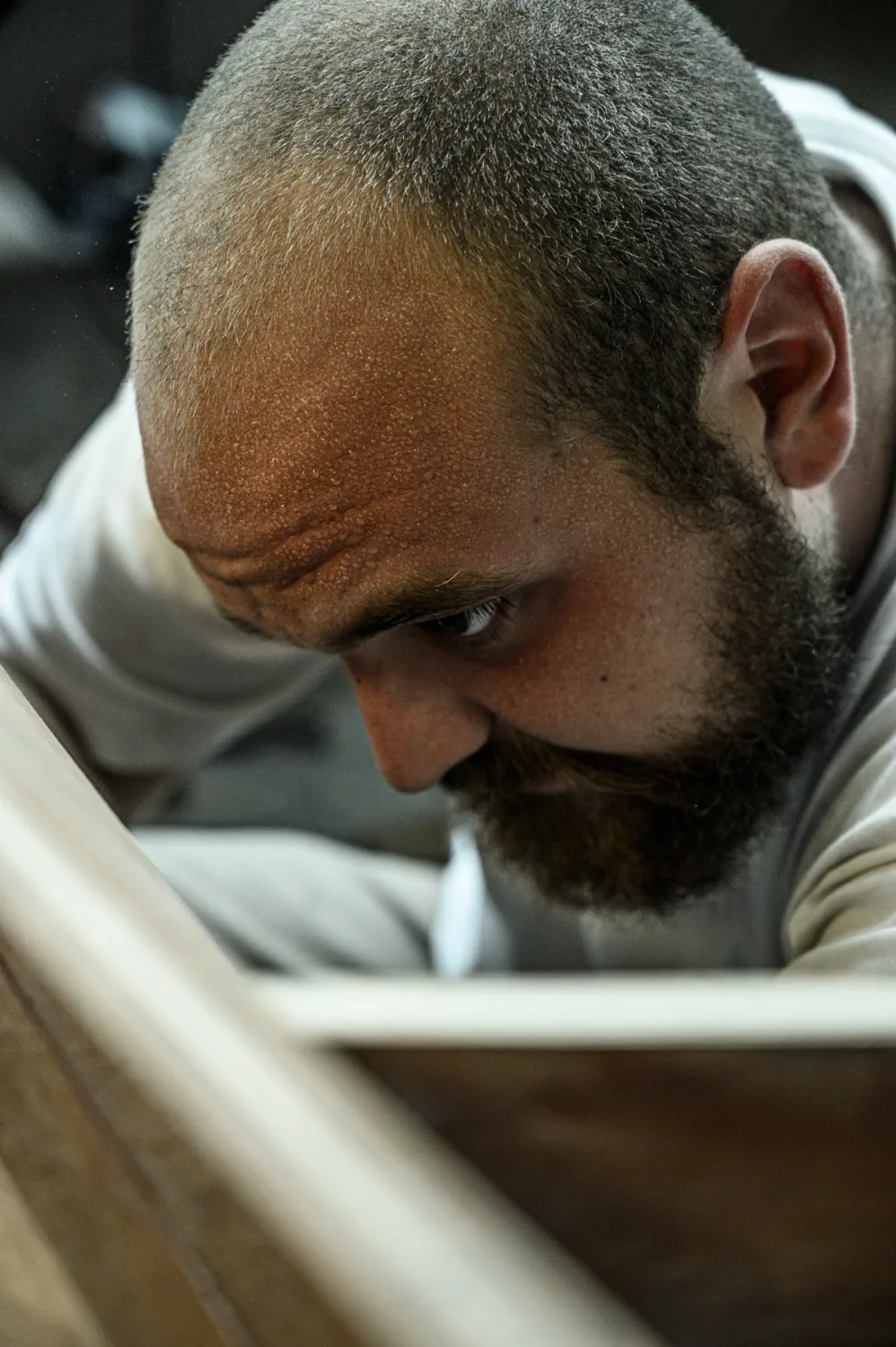 Close-up of a bearded boatbuilder inspecting a hull frame with full concentration — commercial and editorial photography by Janina Laszlo, photographer in Munich