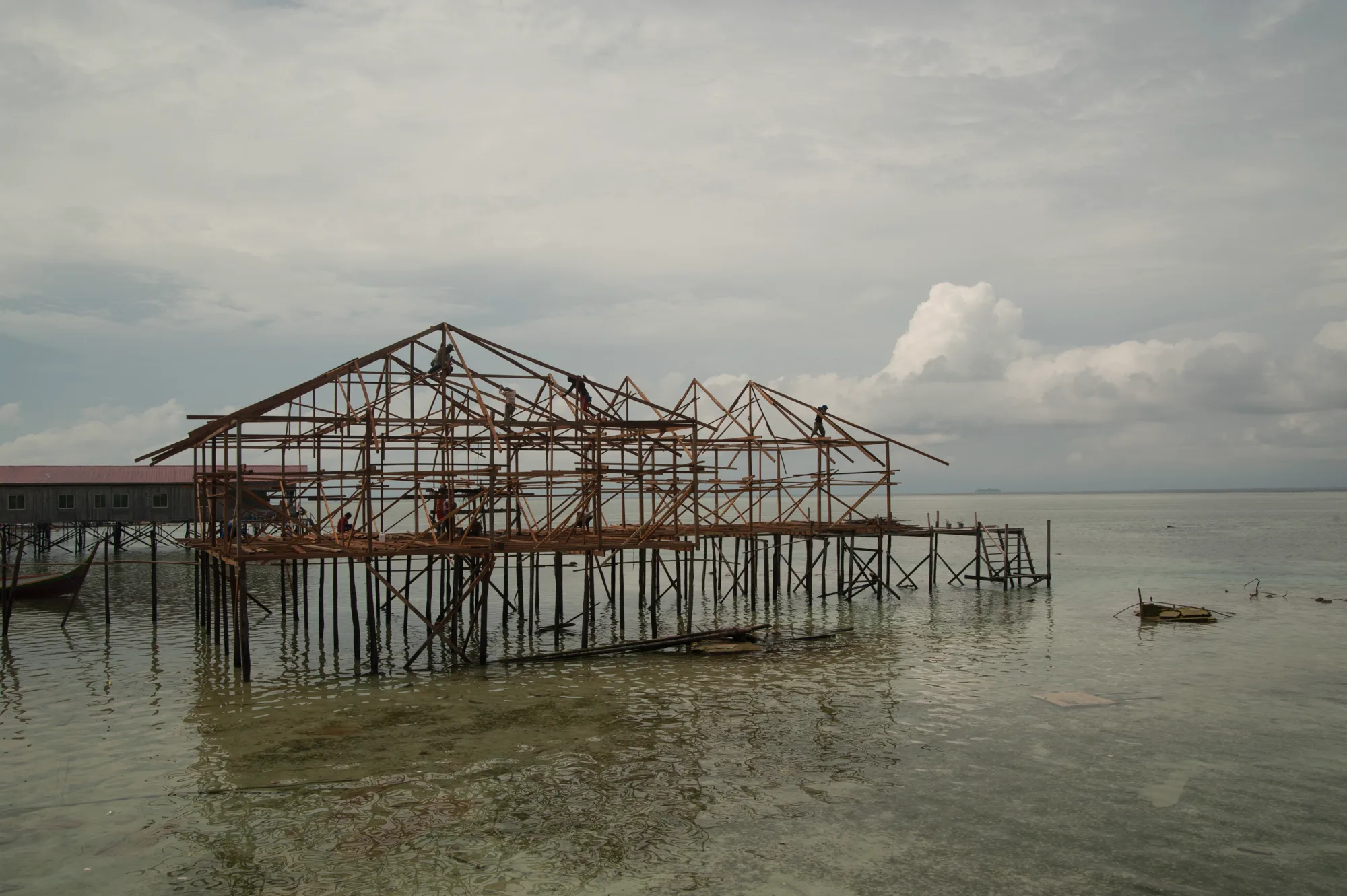 Workers building the timber frame of a stilt house over the sea — Borneo & Pulau Mabul, documentary and travel photography by Janina Laszlo