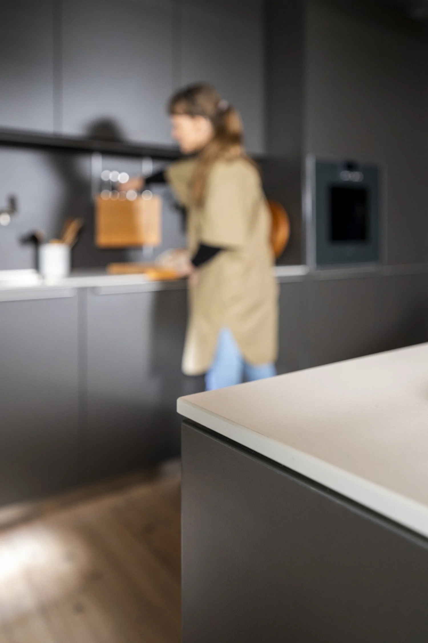 Woman in an apron cooking in a dark bulthaup kitchen, lifestyle campaign image — campaign photography by Janina Laszlo, Munich