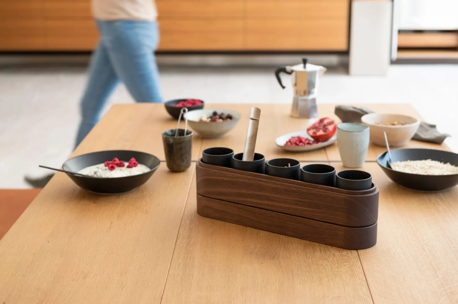 Breakfast table with bulthaup oak caddy and bowls, a passer-by in motion — campaign photography by Janina Laszlo, Munich