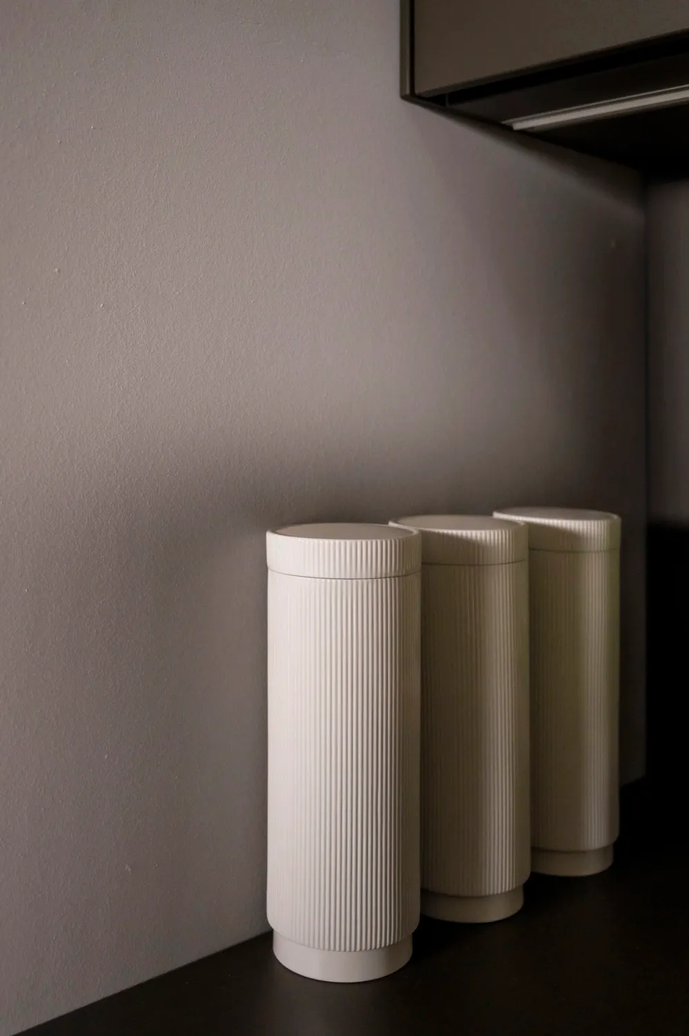 White ribbed porcelain vessels on a dark bulthaup counter — campaign photography by Janina Laszlo, Munich