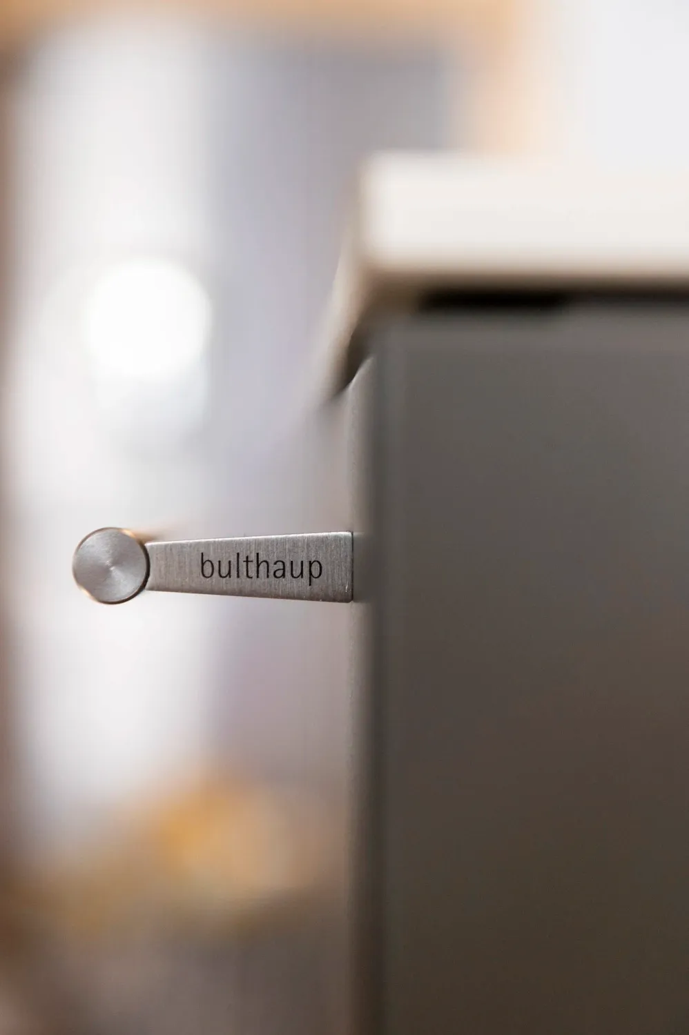 Slim metal handle on a dark bulthaup cabinet front — campaign photography by Janina Laszlo, Munich
