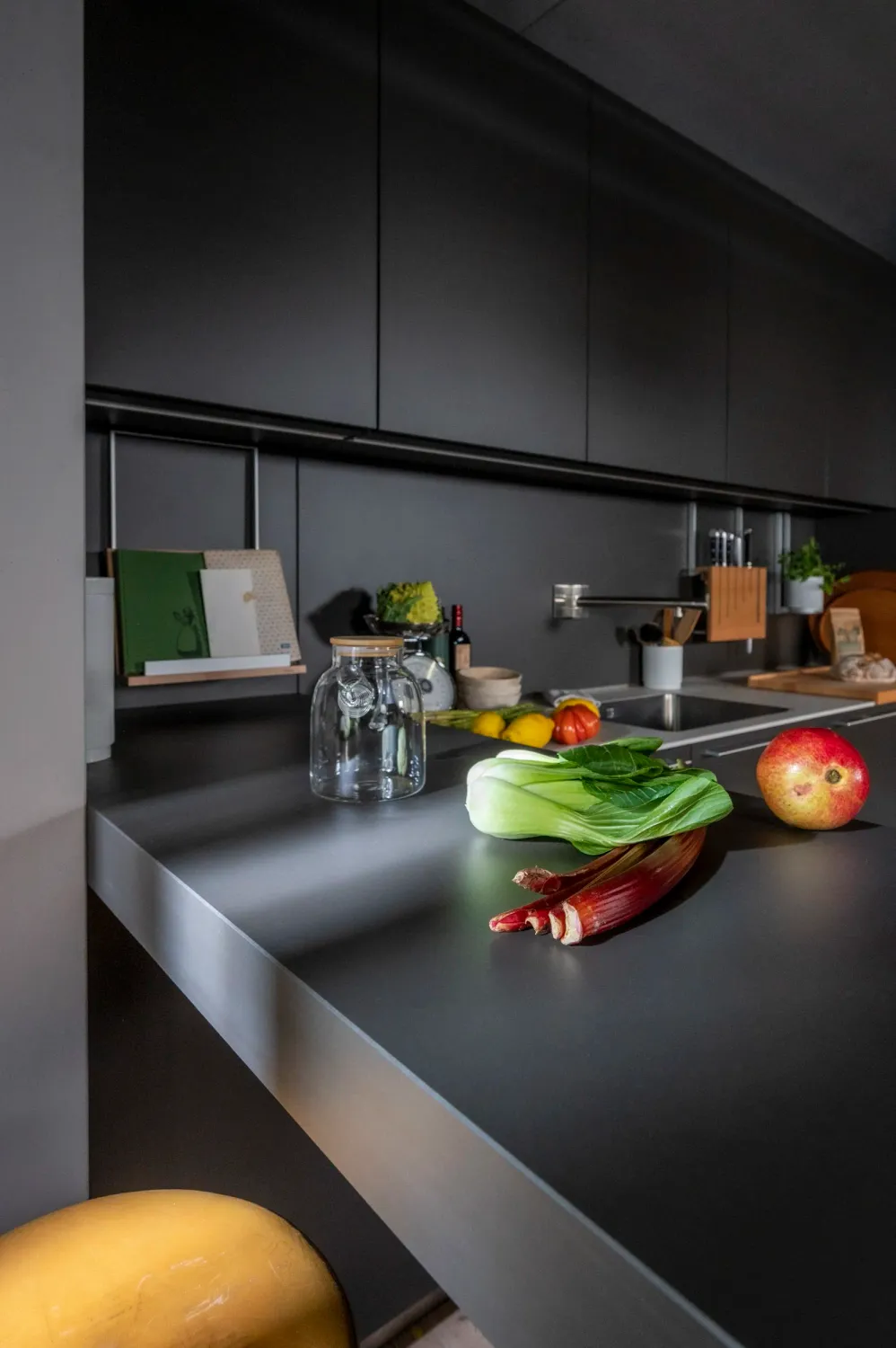Dark bulthaup kitchen with fresh vegetables on the island — campaign photography by Janina Laszlo, Munich
