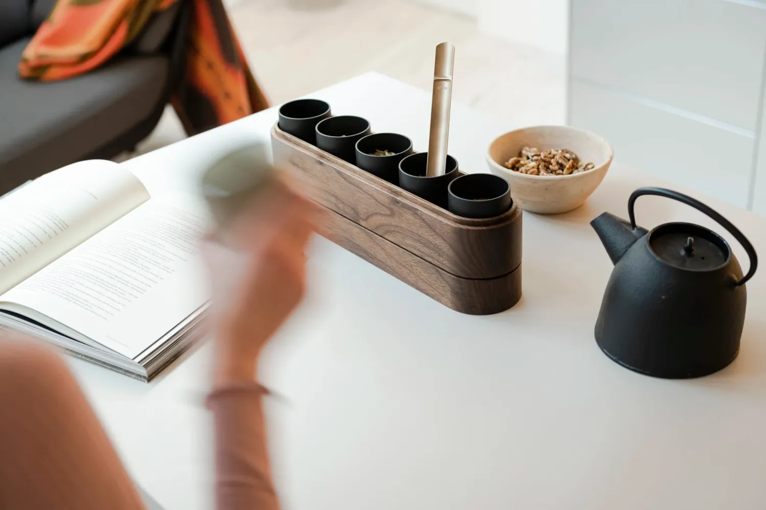 Hands writing at a table with bulthaup oak box and black teapot — campaign photography by Janina Laszlo, Munich