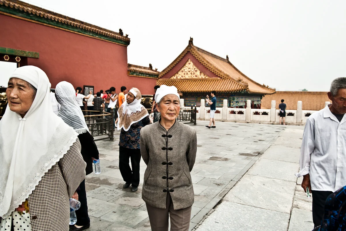 Elderly women in white headscarves in a courtyard of the Forbidden City, Beijing — China, documentary and travel photography by Janina Laszlo