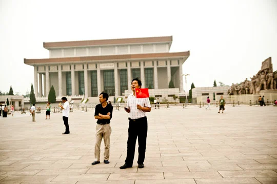 Man with a small Chinese flag on Tiananmen Square before the Mausoleum of Mao Zedong, Beijing — China, documentary and travel photography by Janina Laszlo