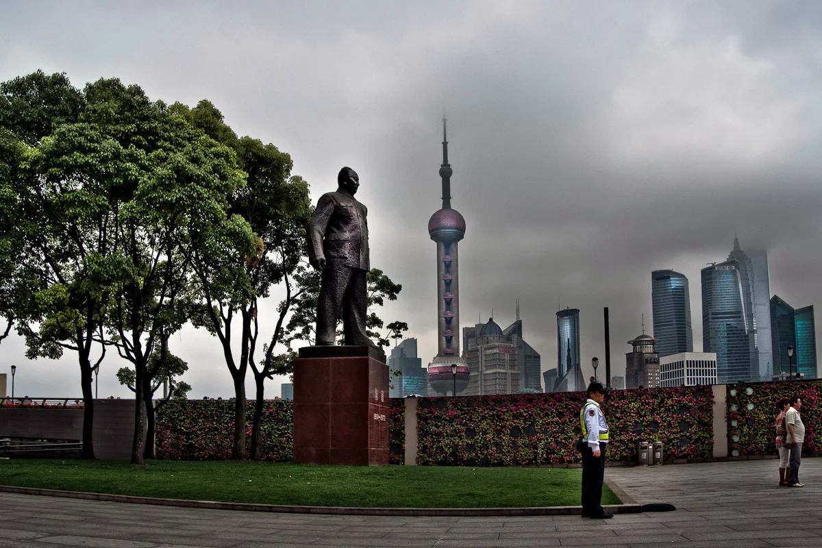 Statue on the Bund before the Oriental Pearl Tower and Pudong skyline in rain clouds, Shanghai — China, documentary and travel photography by Janina Laszlo