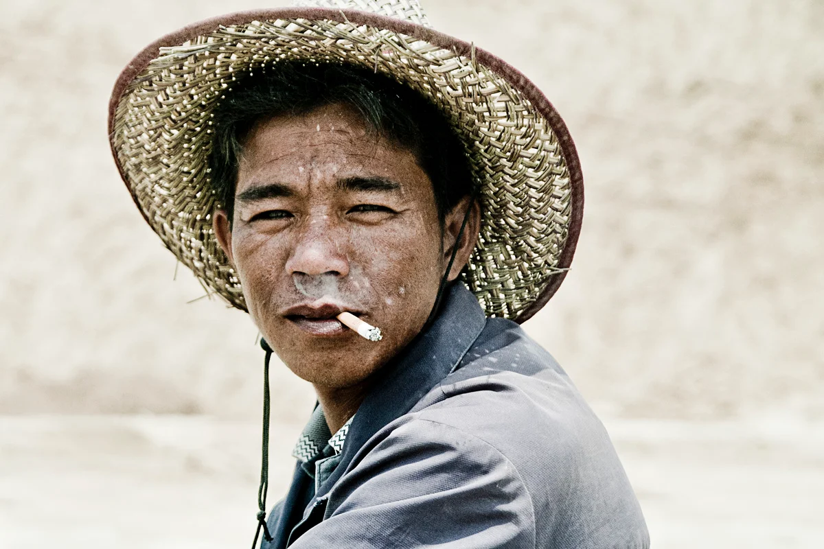Man in a woven straw hat with a cigarette, Hainan — China, documentary and travel photography by Janina Laszlo