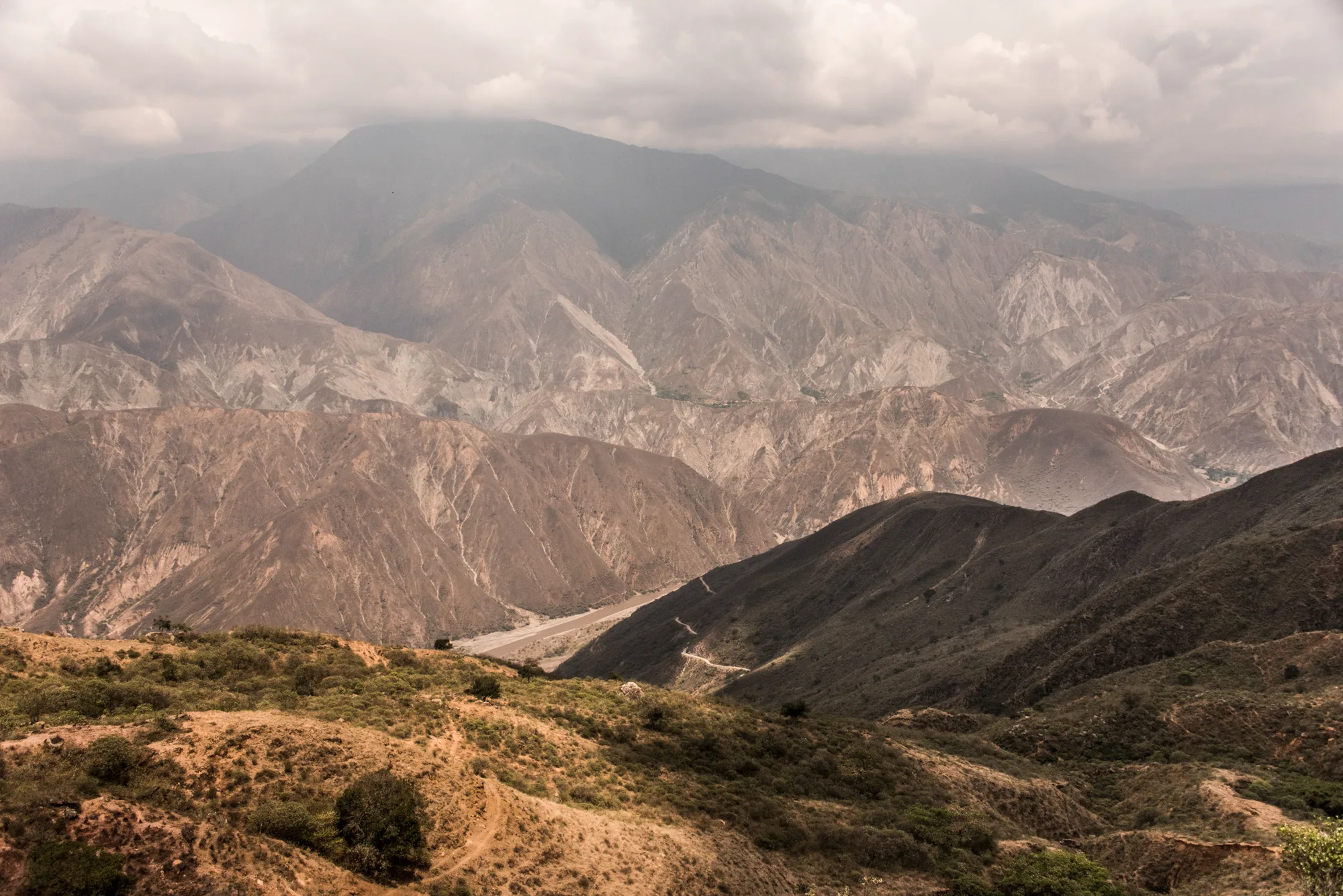 Layers of bare mountain ridges and a river valley under clouds, Chicamocha Canyon — Colombia, travel and documentary photography by Janina Laszlo