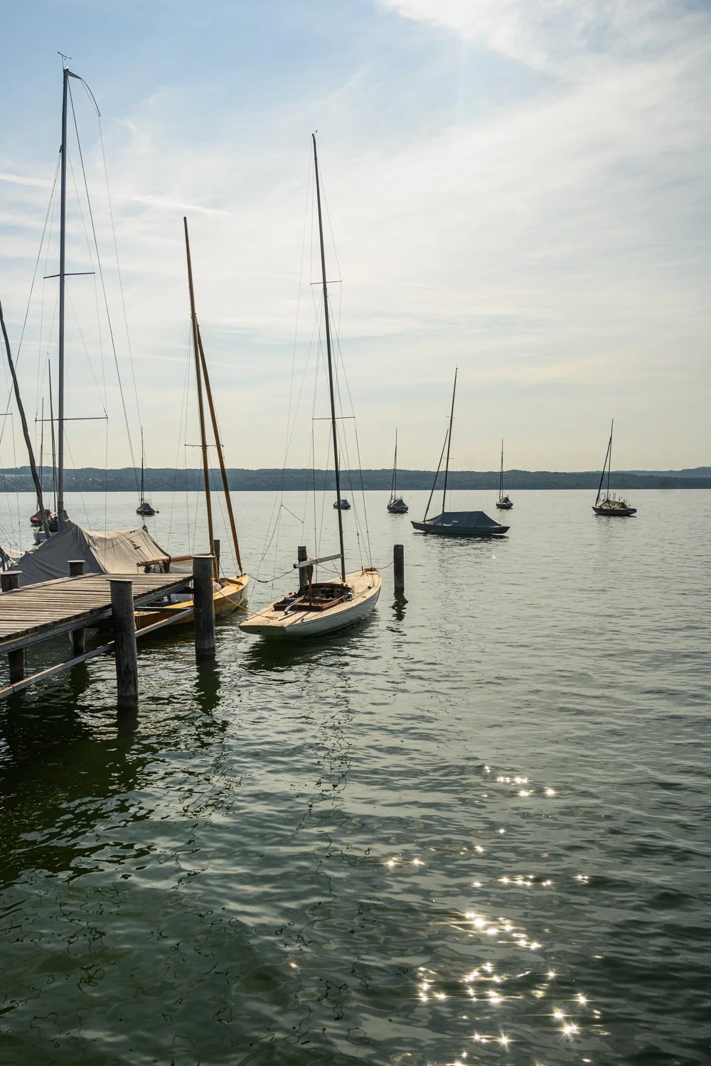 Wooden sailing boats moored at a jetty on the Ammersee in evening light — boatbuilding reportage by Janina Laszlo, photographer in Munich