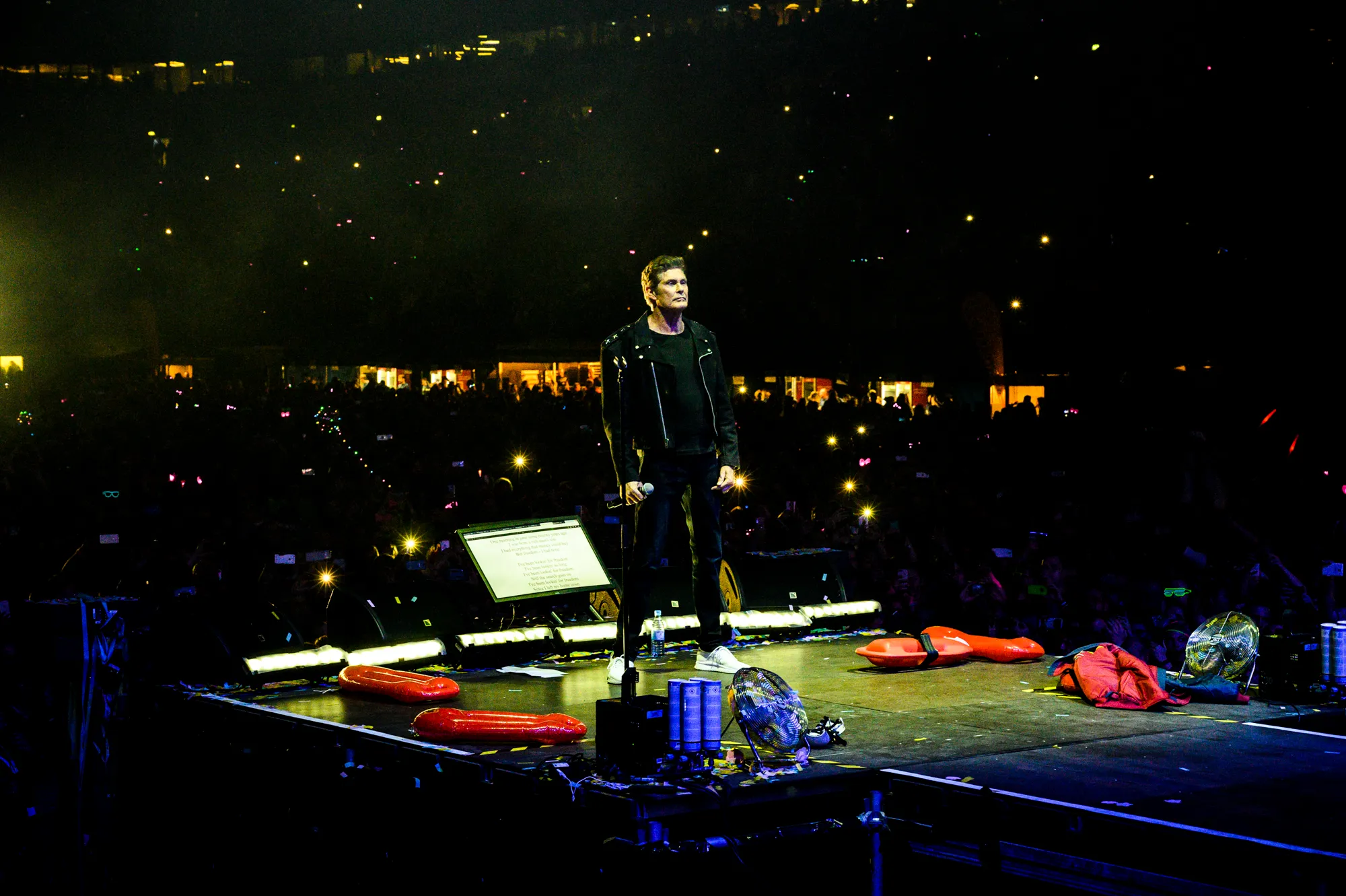 David Hasselhoff on stage with a microphone in front of a crowd holding up phone lights — editorial concert photography by German photographer Janina Laszlo