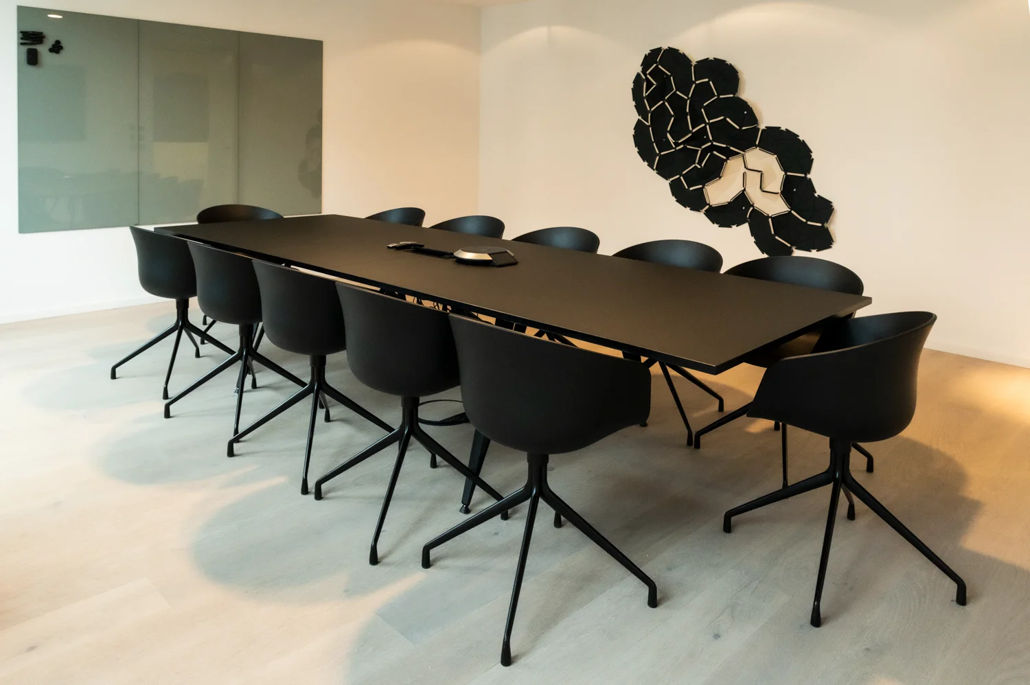 Empty conference room with a long black table, black chairs and a sculptural acoustic wall panel, Frankfurt am Main & Munich — Digital+, corporate photography by Janina Laszlo