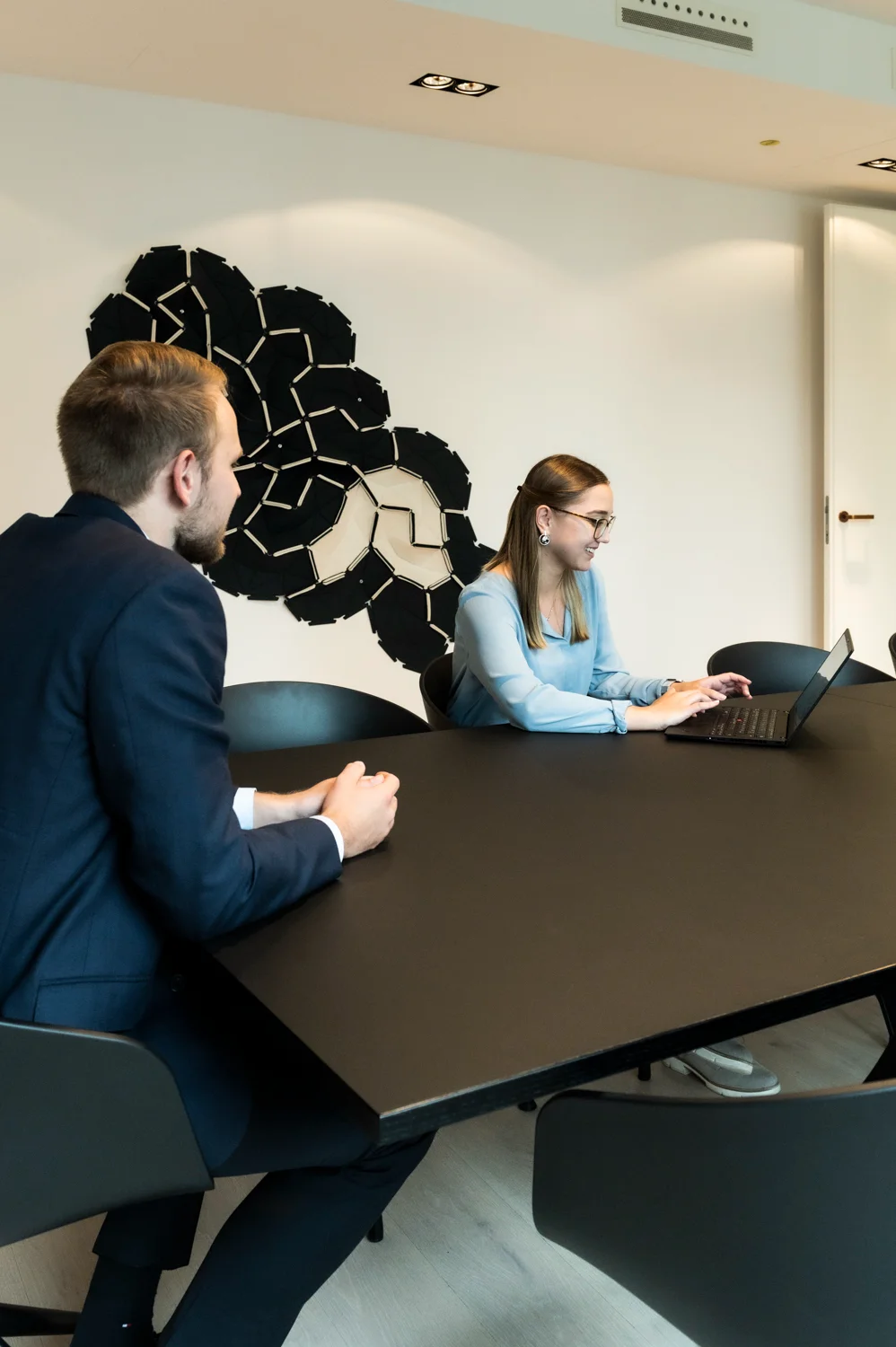 Two colleagues at the black conference table, one typing on a laptop, Frankfurt am Main & Munich — Digital+, corporate photography by Janina Laszlo