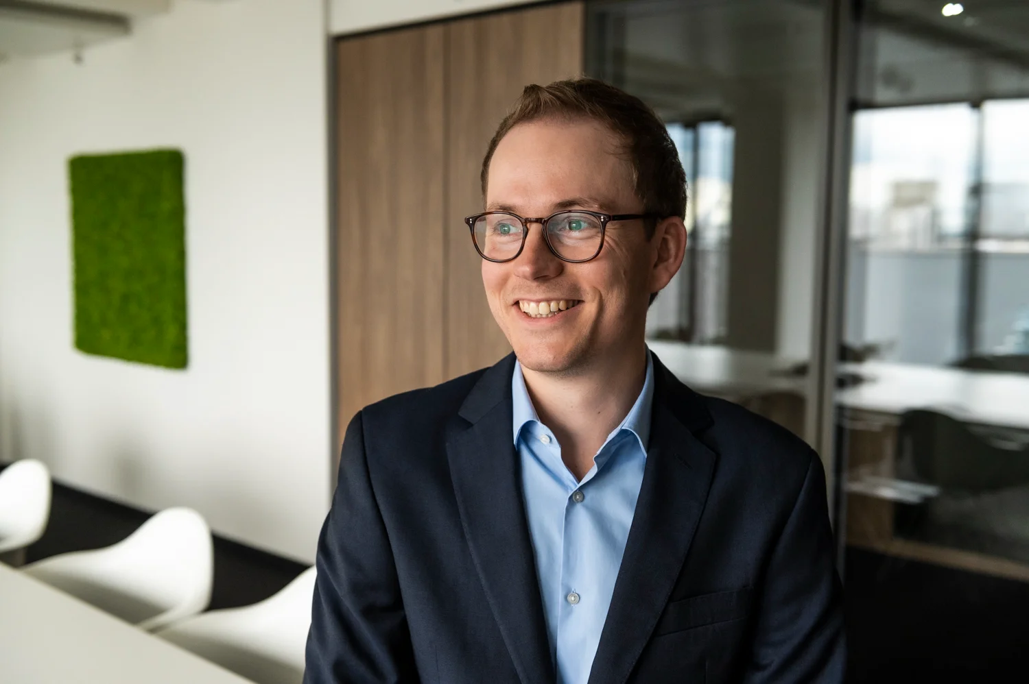 Smiling employee with glasses and a navy blazer, business portrait in the office, Frankfurt am Main & Munich — Digital+, corporate photography by Janina Laszlo