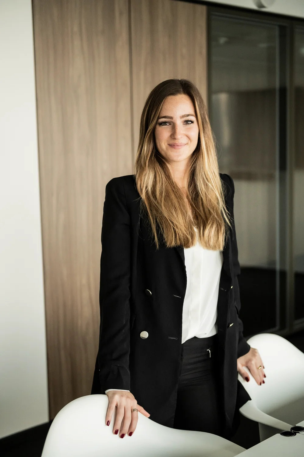 Employee in a black blazer standing at white conference chairs, business portrait, Frankfurt am Main & Munich — Digital+, corporate photography by Janina Laszlo