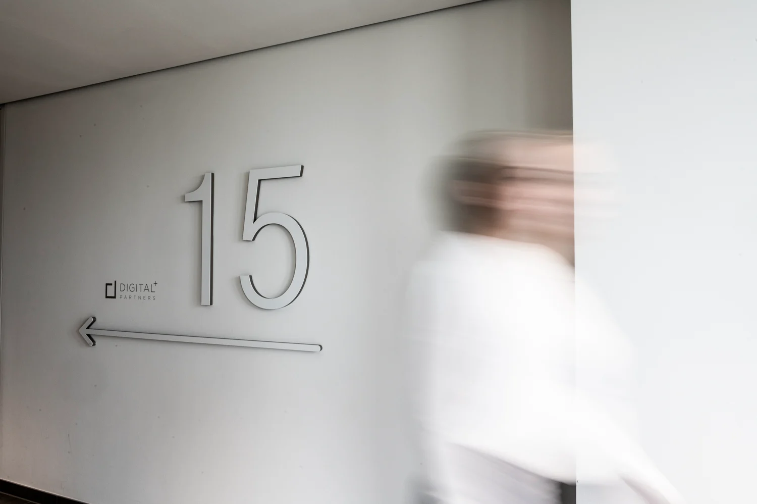 Digital+ Partners floor sign with a large number 15 and a colleague walking past in motion blur, Frankfurt am Main — Digital+, corporate photography by Janina Laszlo