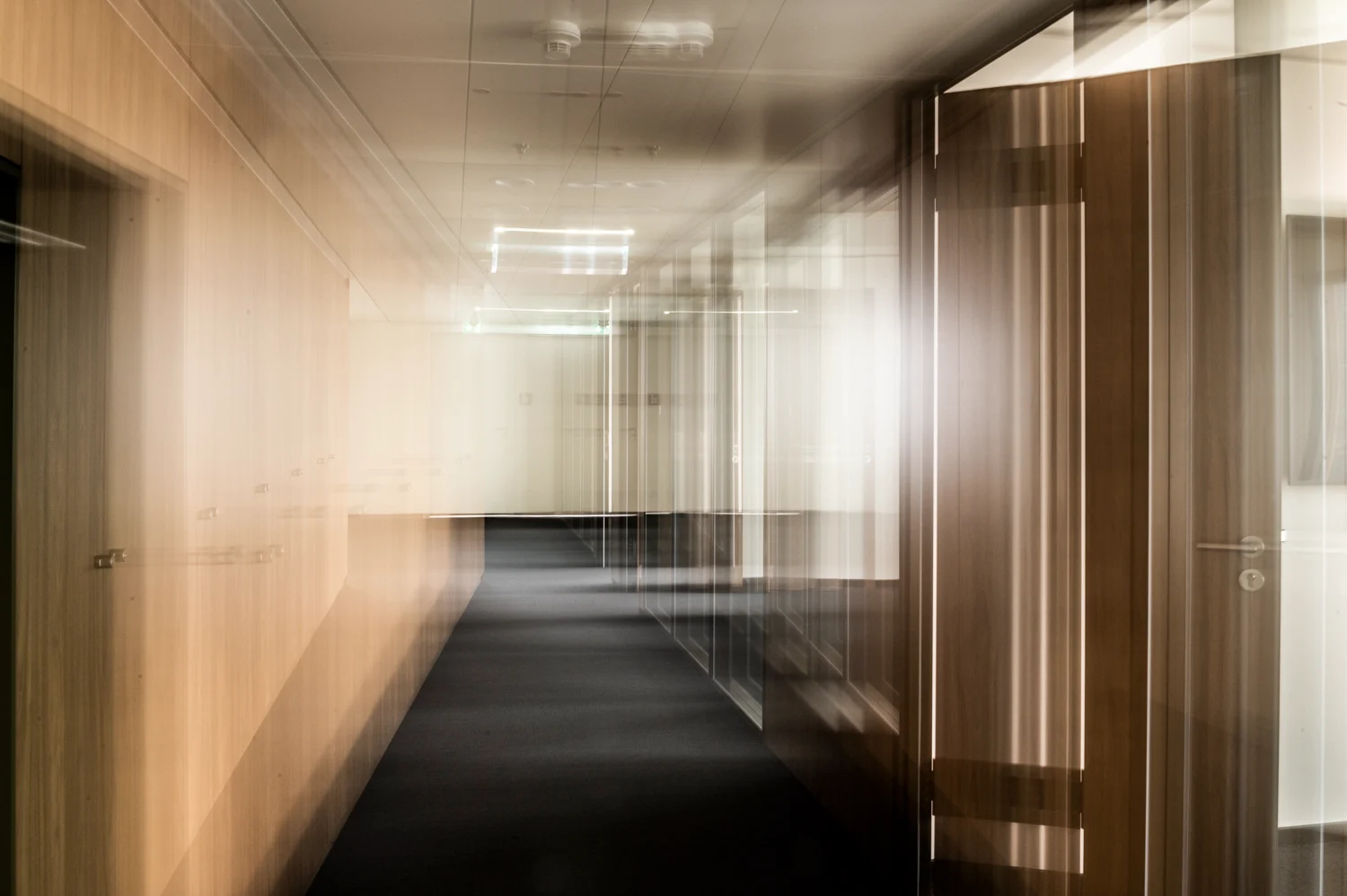Office corridor with walnut panelling and glass doors in multiple-exposure motion blur, Frankfurt am Main — Digital+, corporate photography by Janina Laszlo