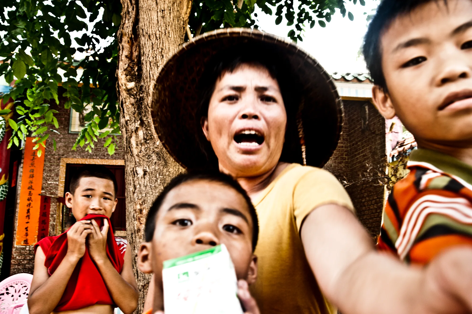 Woman in a straw hat and boys cheering — Dragon Boat Festival Hainan, documentary photography by Janina Laszlo