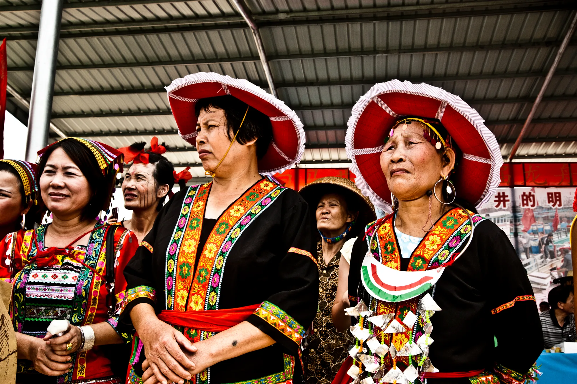 Women in traditional embroidered costumes and red hats — Dragon Boat Festival Hainan, documentary photography by Janina Laszlo