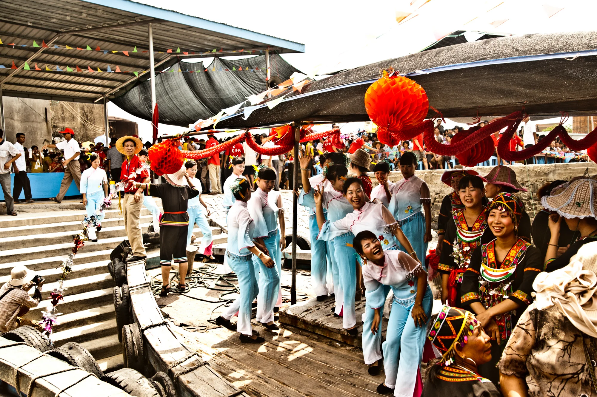Performers in light blue costumes waiting under a festival canopy — Dragon Boat Festival Hainan, documentary photography by Janina Laszlo