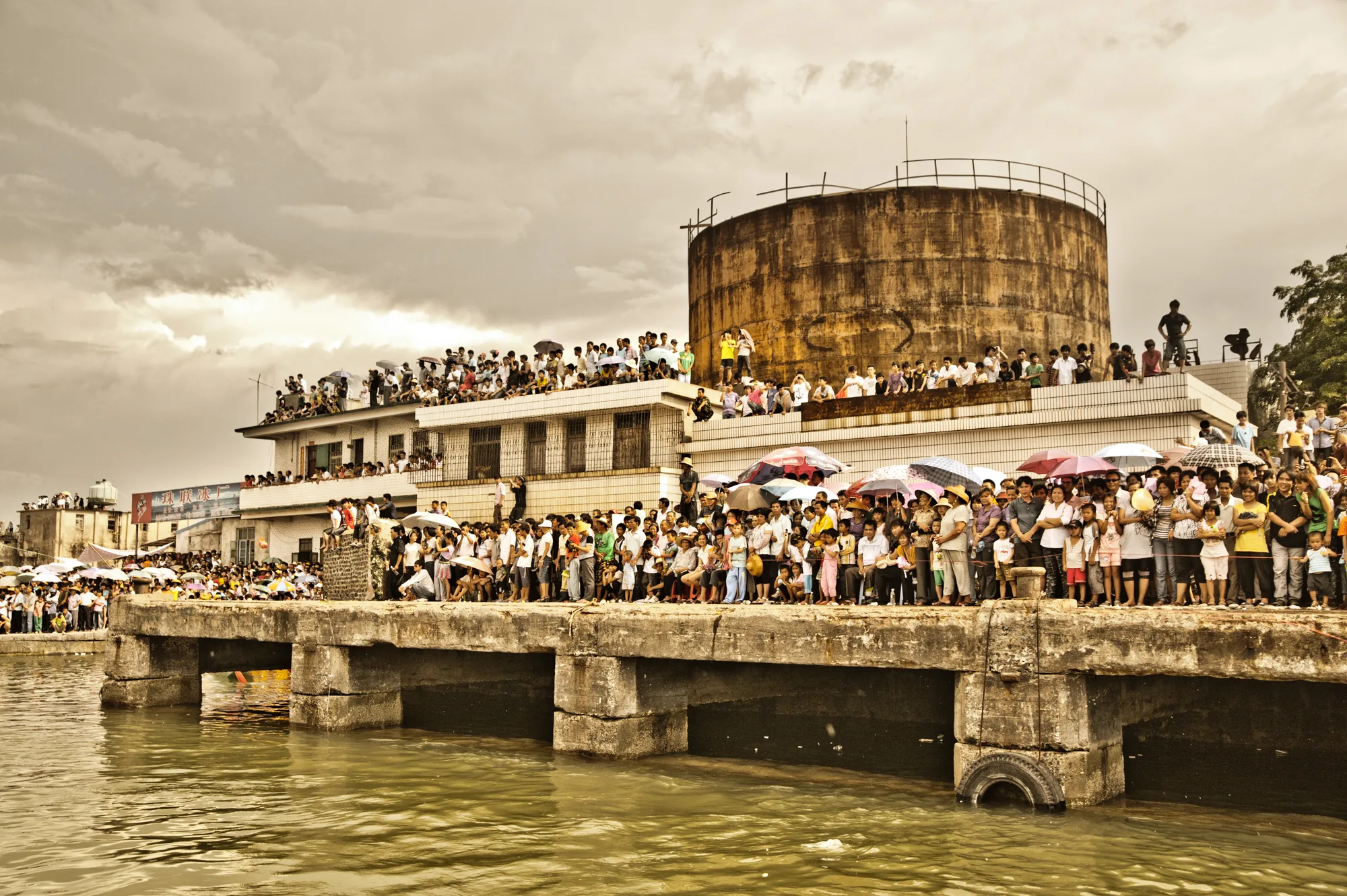 Crowds lining the pier by an old water tower to watch the races — Dragon Boat Festival Hainan, documentary photography by Janina Laszlo