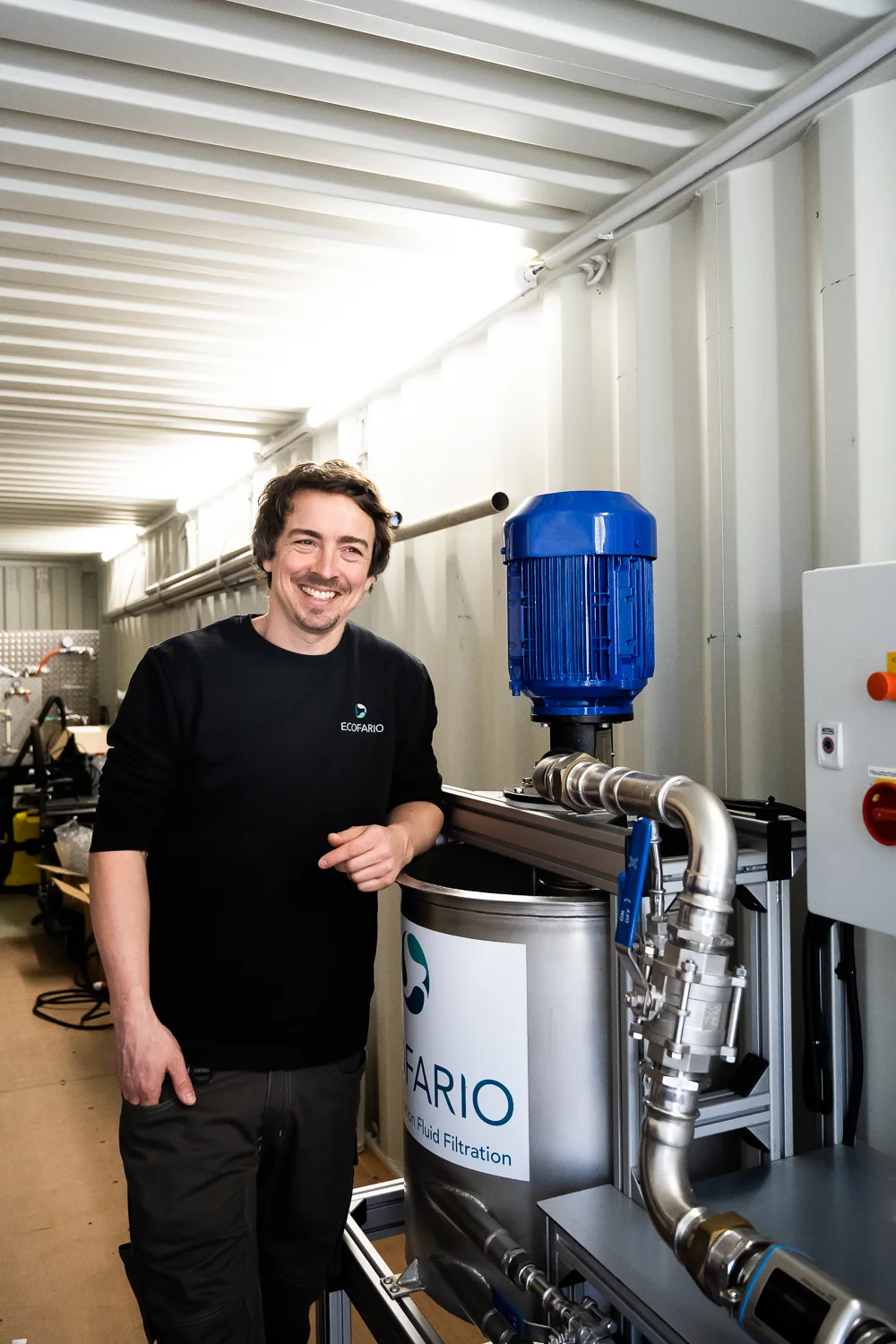 Engineer standing among water treatment equipment in a container — ECOFARIO, corporate portrait and industrial reportage photography by Janina Laszlo