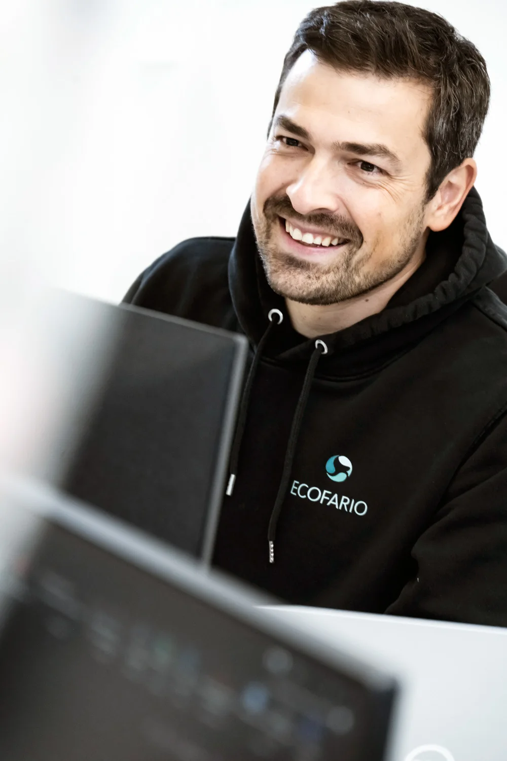 Smiling team member at a laptop — ECOFARIO, corporate portrait and industrial reportage photography by Janina Laszlo