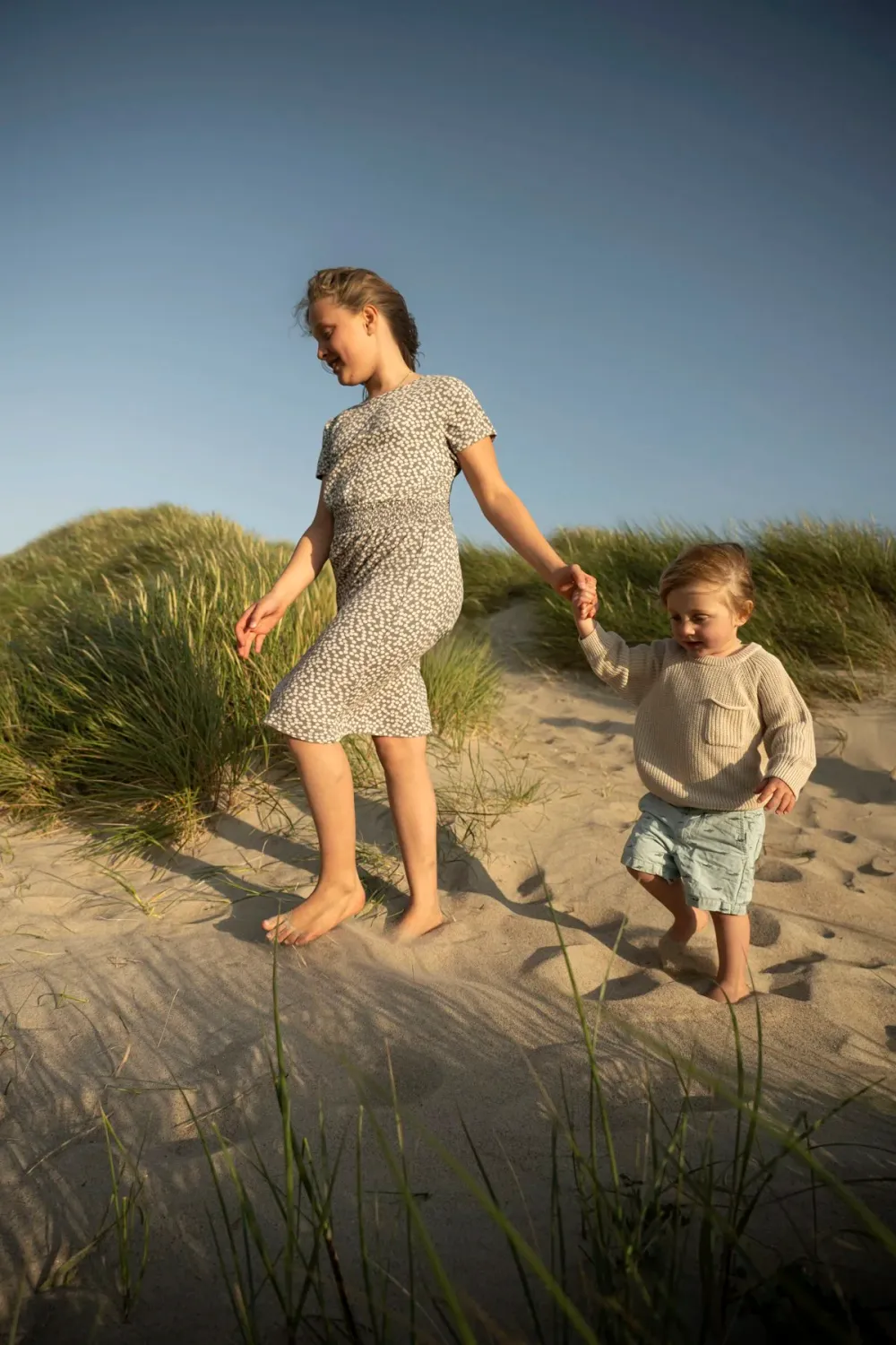 Mother leading her son by the hand through the dunes at dusk — Ernsting's family kidswear, Klitmøller, Denmark — campaign photography by Janina Laszlo, Munich