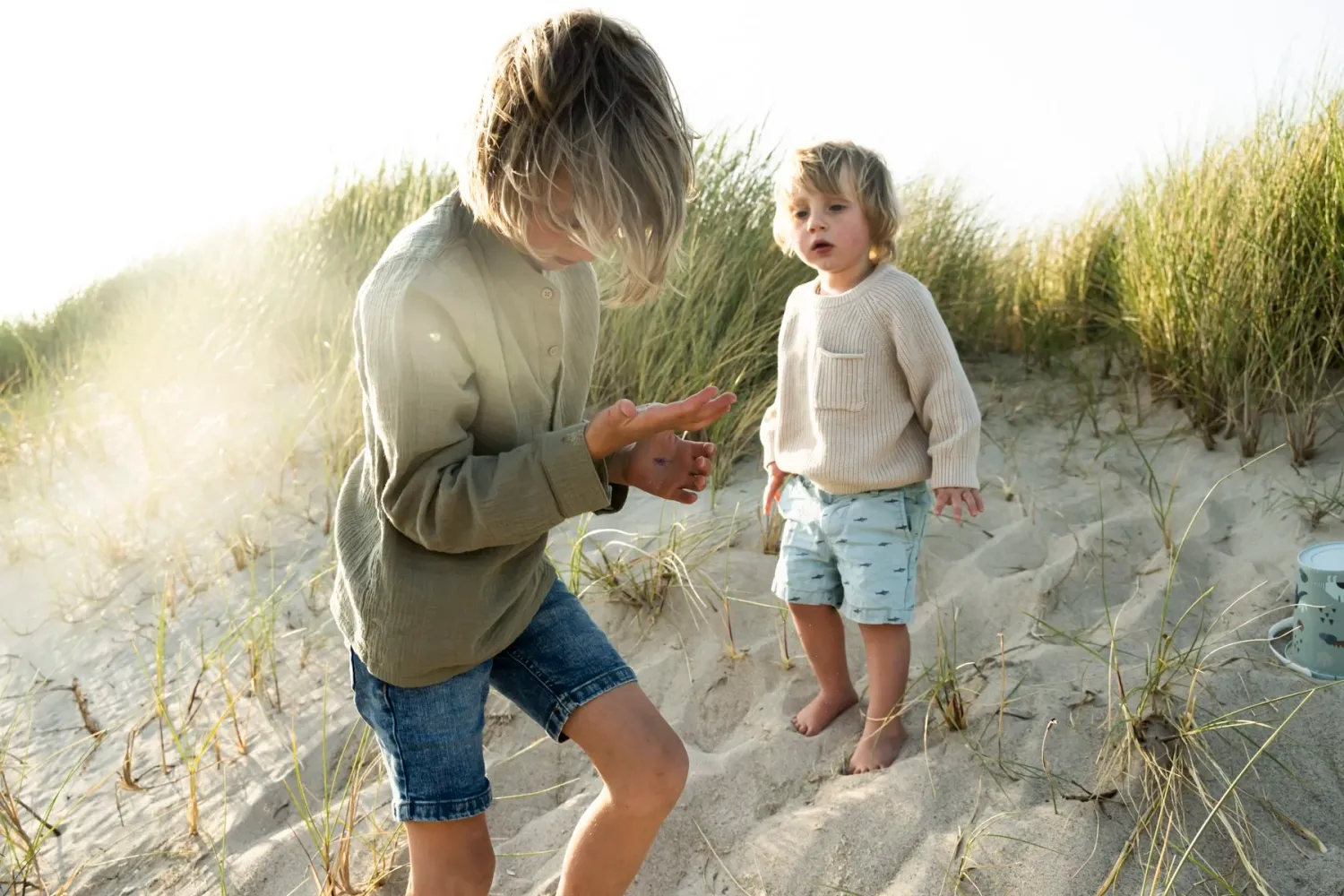 Older brother showing something to his little sibling on the beach — Ernsting's family kidswear, Klitmøller, Denmark — campaign photography by Janina Laszlo, Munich
